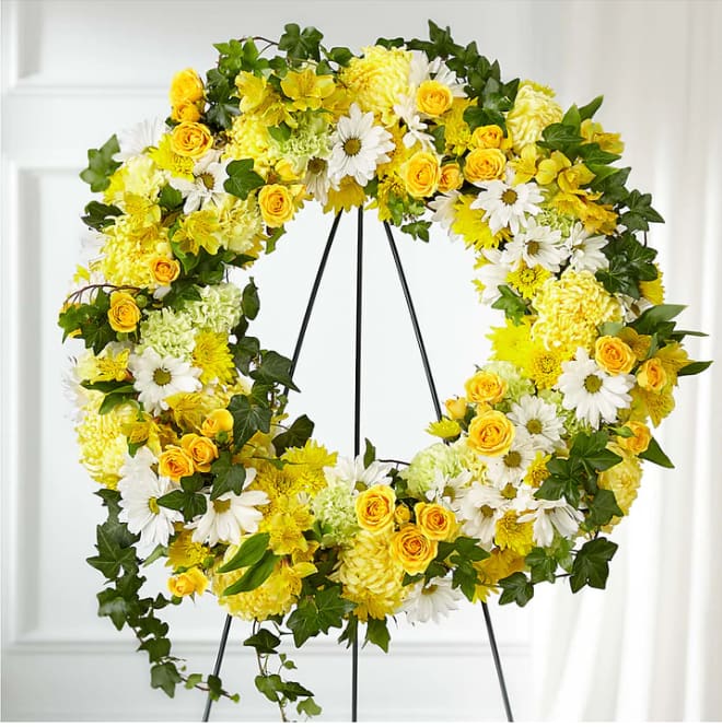 Yellow and white floral wreath on a black stand