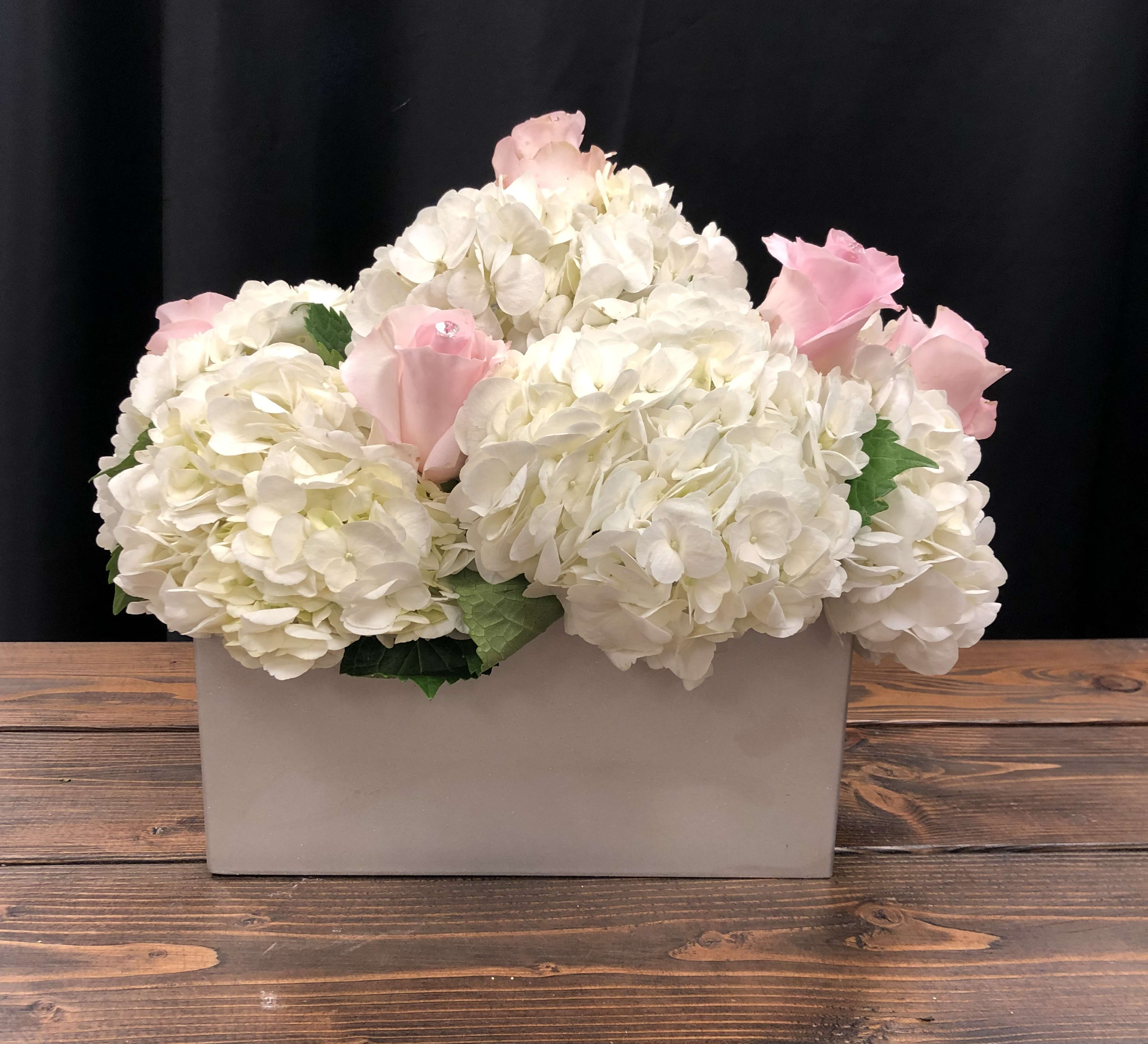 White hydrangeas with pink roses in a rectangular vase