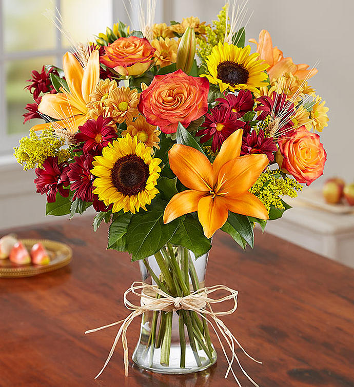 Fall Fields of Europe - Clear glass vase with vibrant colors of orange lillies, sunflowers, orange roses, solidago,  rust daisy pomps