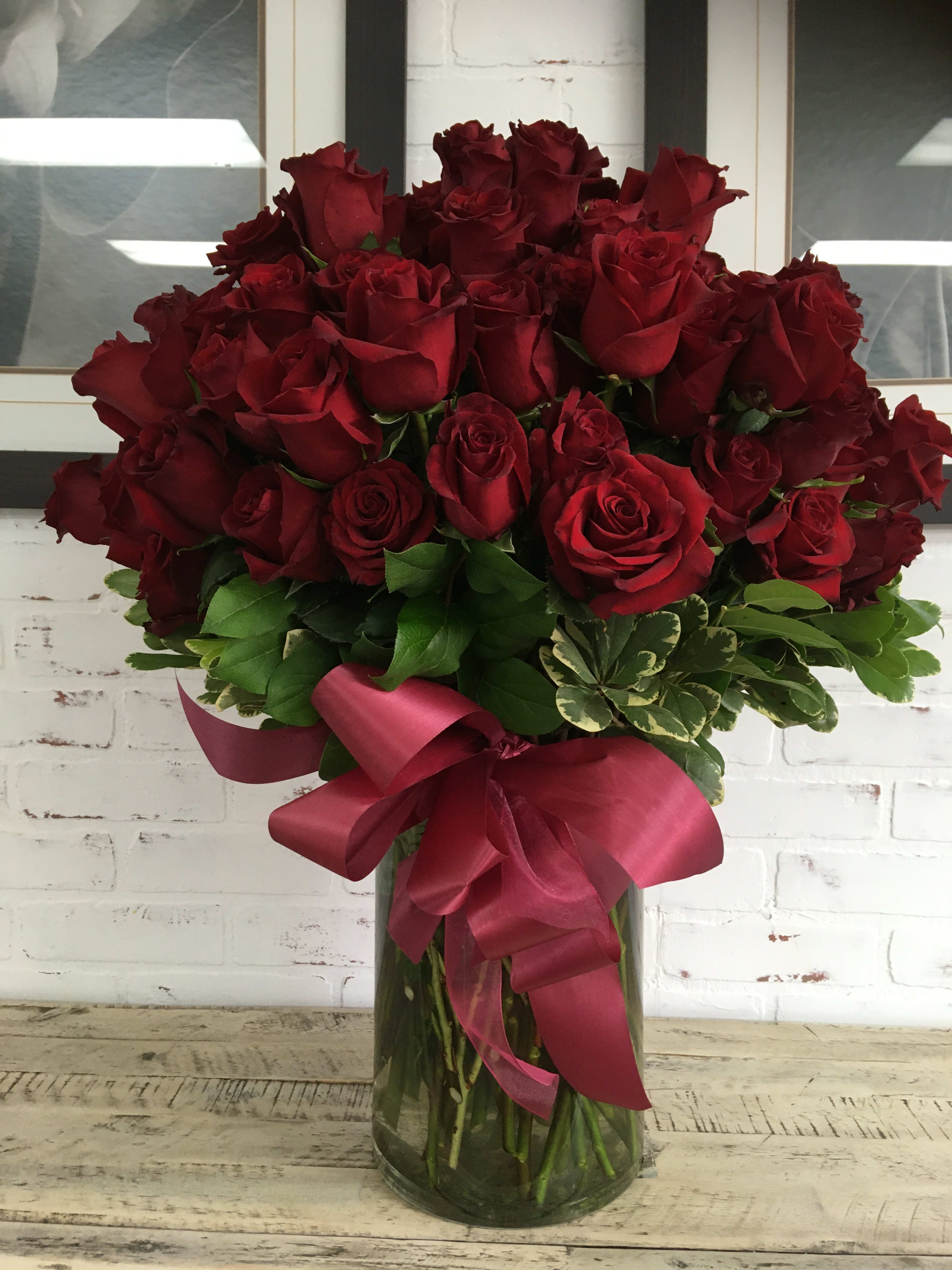 Bouquet of red roses in a glass vase with a burgundy ribbon