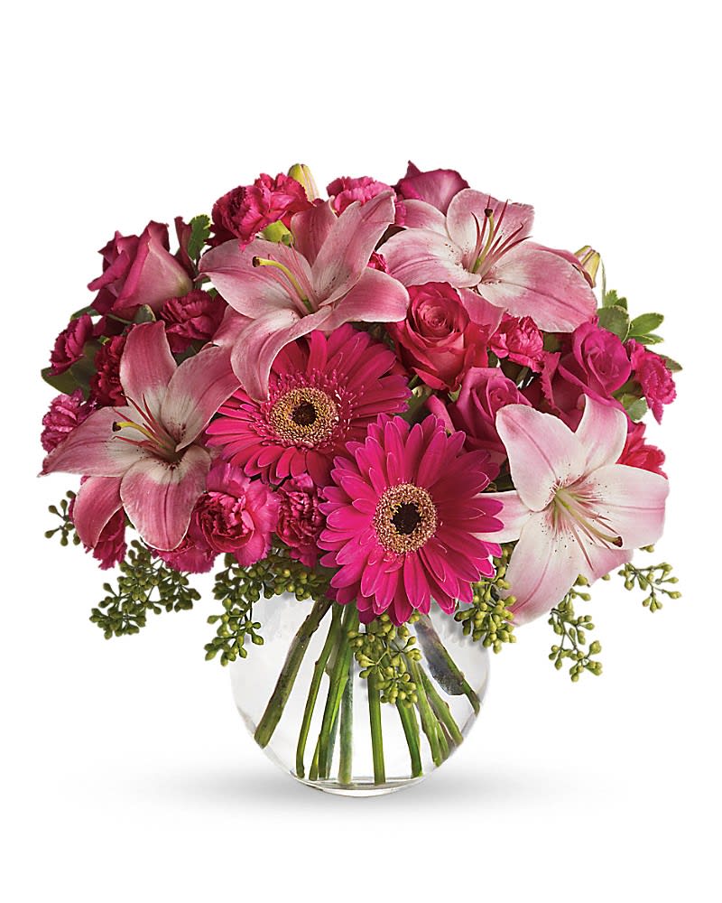 Pink lilies, gerbera daisies, roses, and carnations in a glass vase