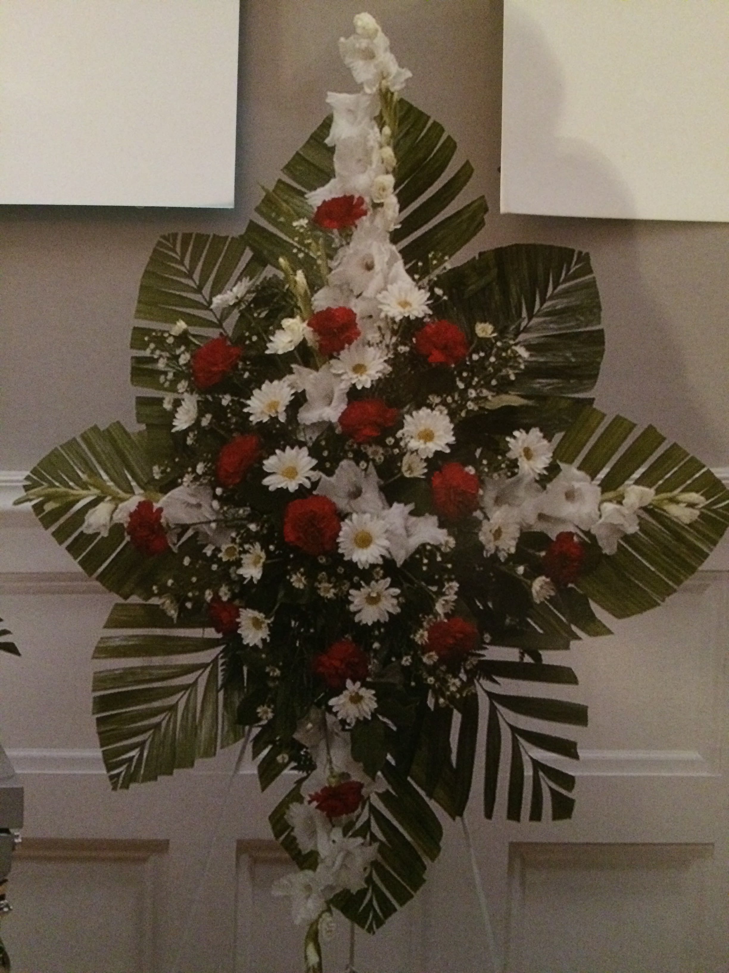 Standing floral spray with white and red flowers and large palm leaves