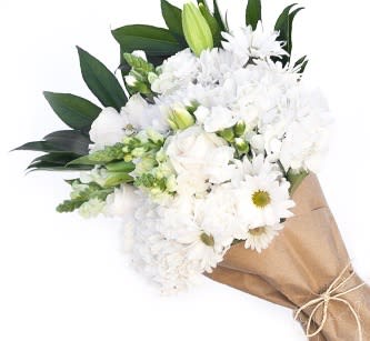 White bouquet with daisies and lilies wrapped in brown paper
