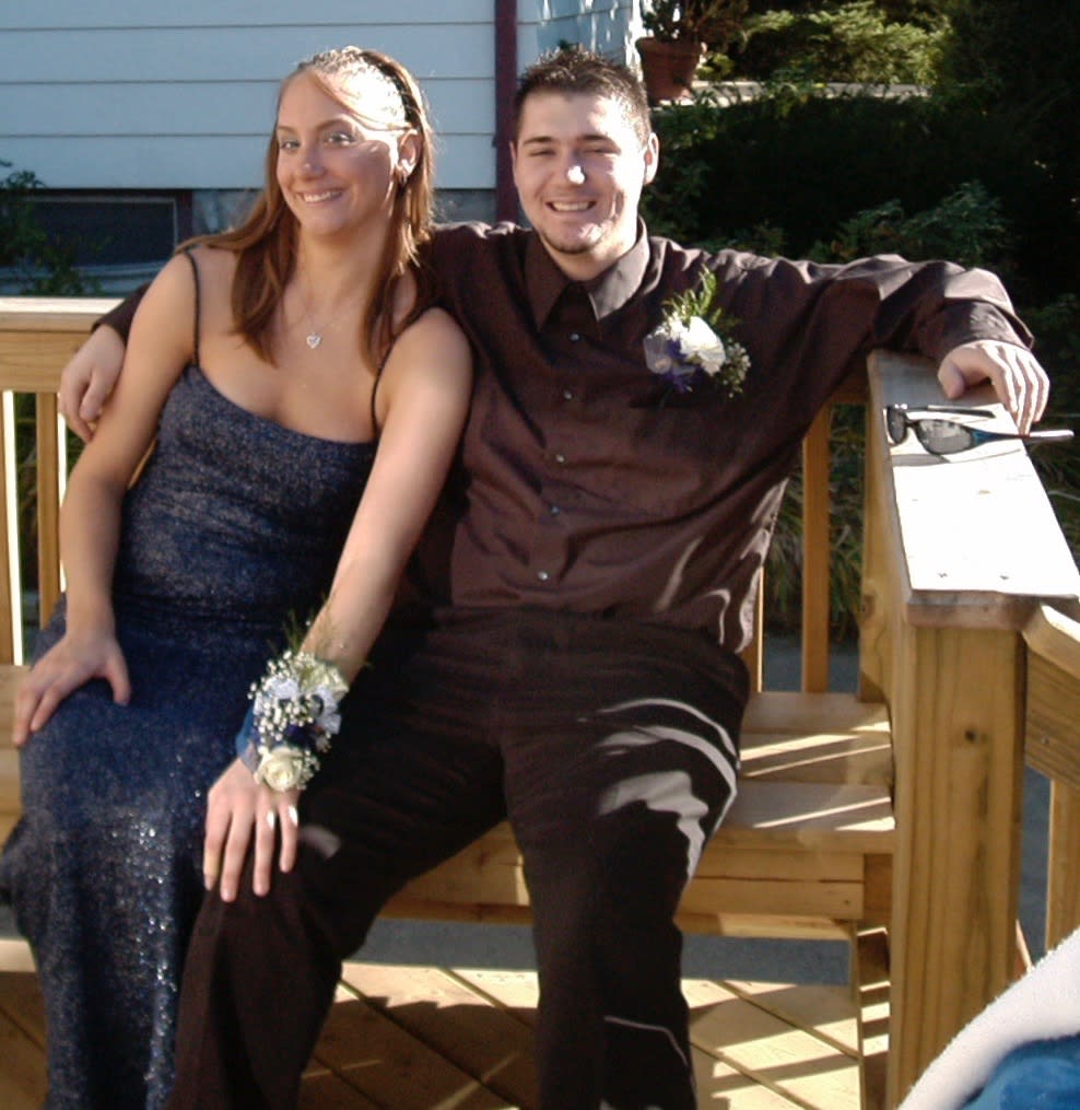 Young couple seated outdoors, each wearing a floral corsage or boutonniere