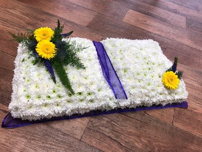 White floral casket spray with yellow flowers and purple ribbon