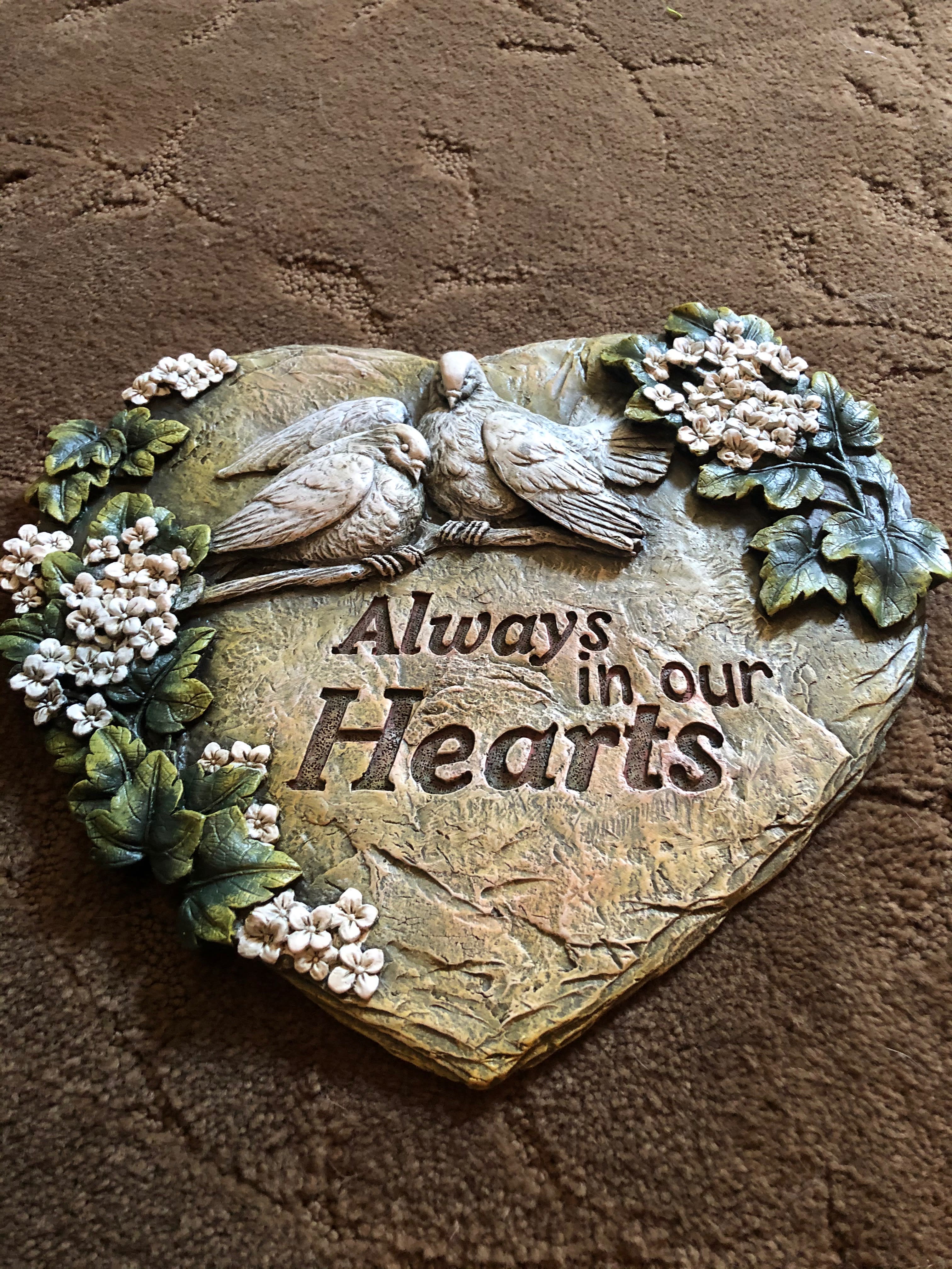Heart-shaped decorative plaque with two birds and flowers, reading "Always in our Hearts"