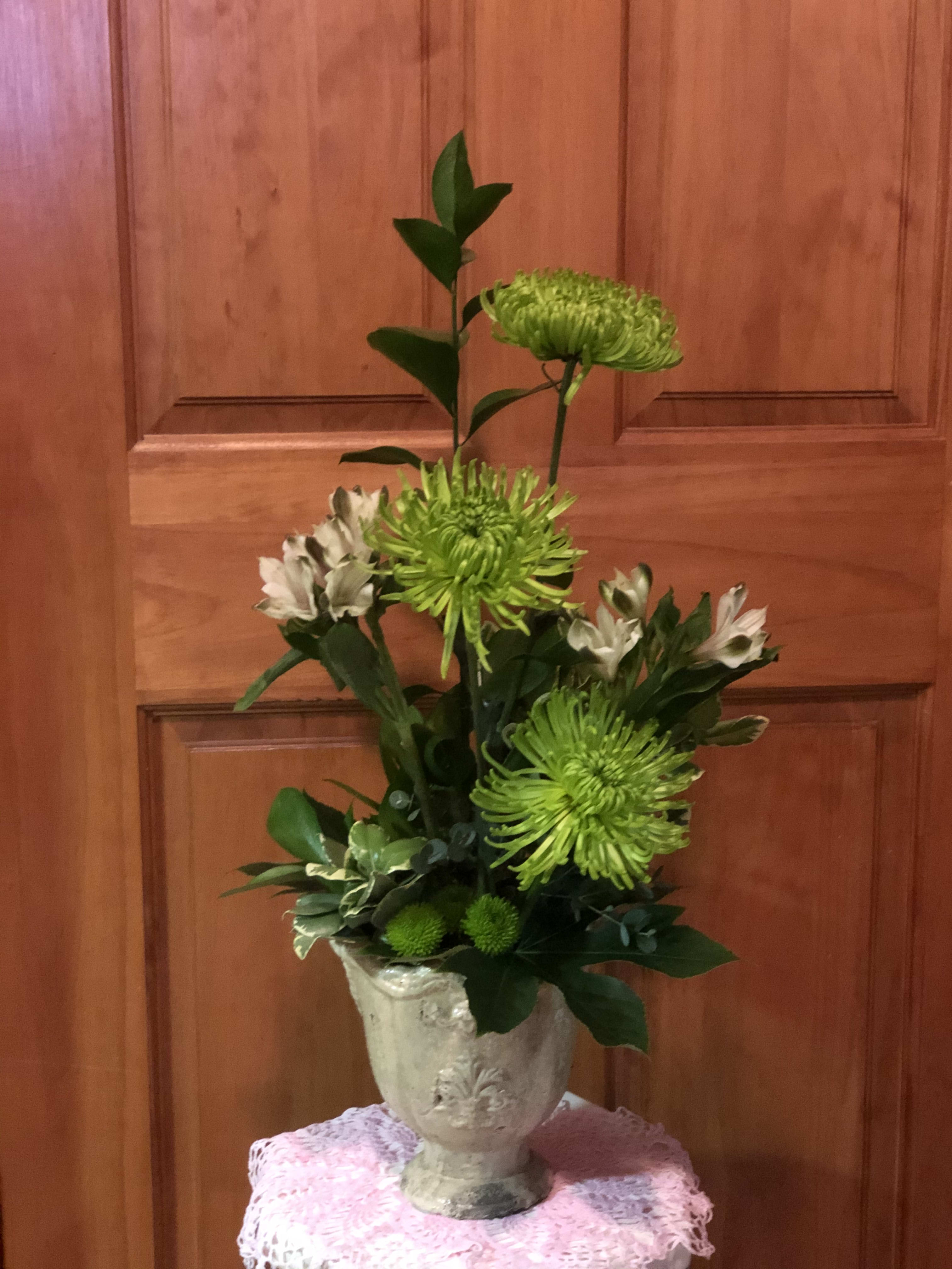 Tall green and white floral arrangement in a decorative urn