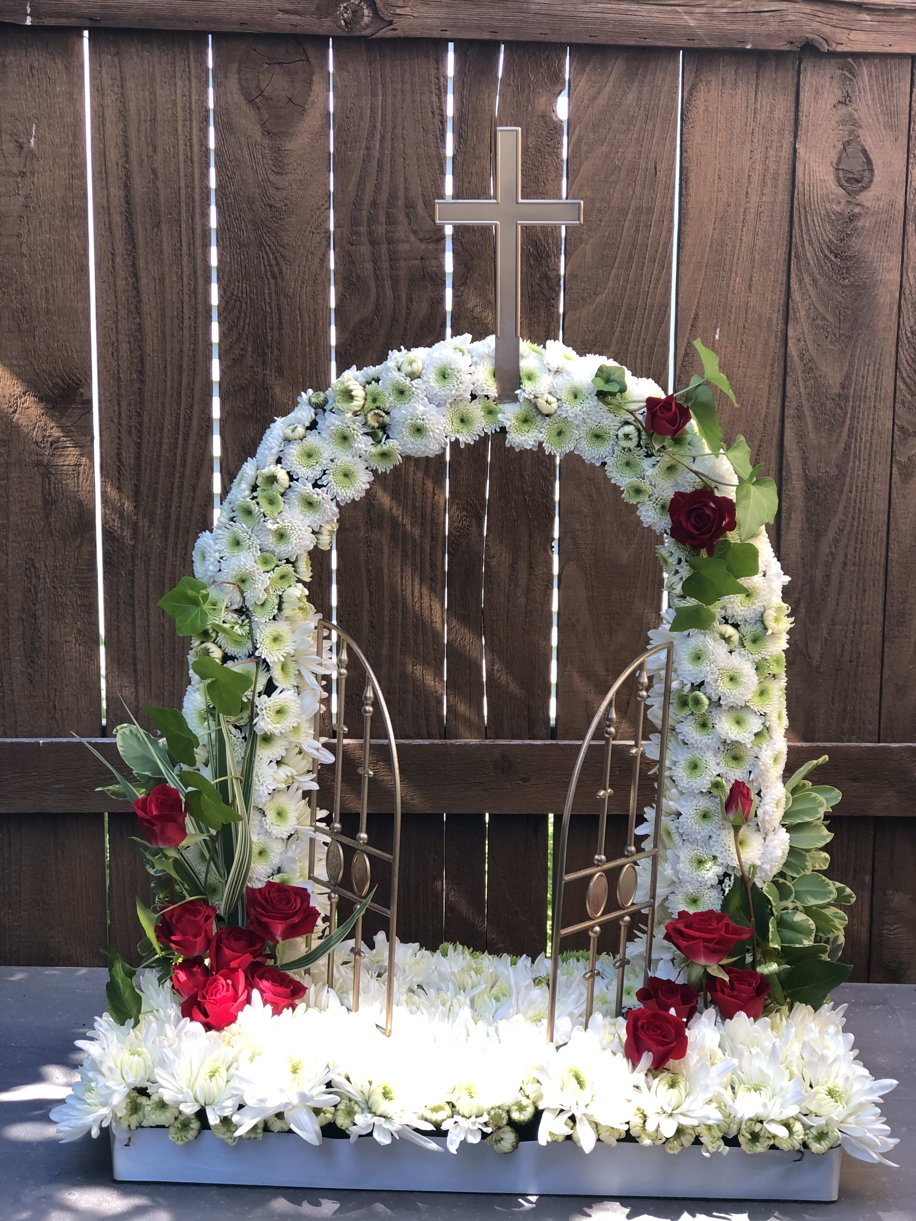White floral funeral wreath with red roses and a cross topper