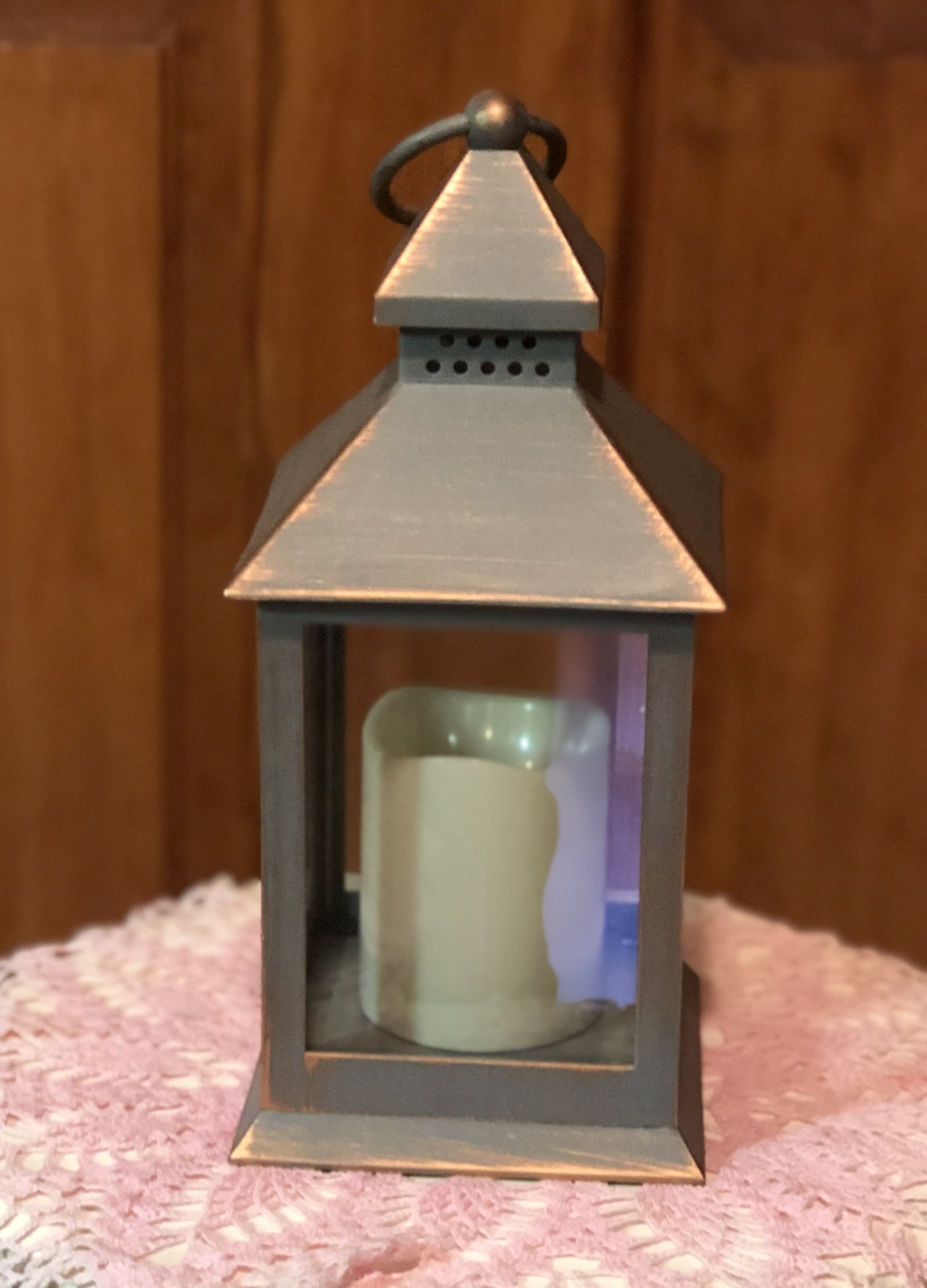 Metal lantern with a candle inside on a pink textured cloth