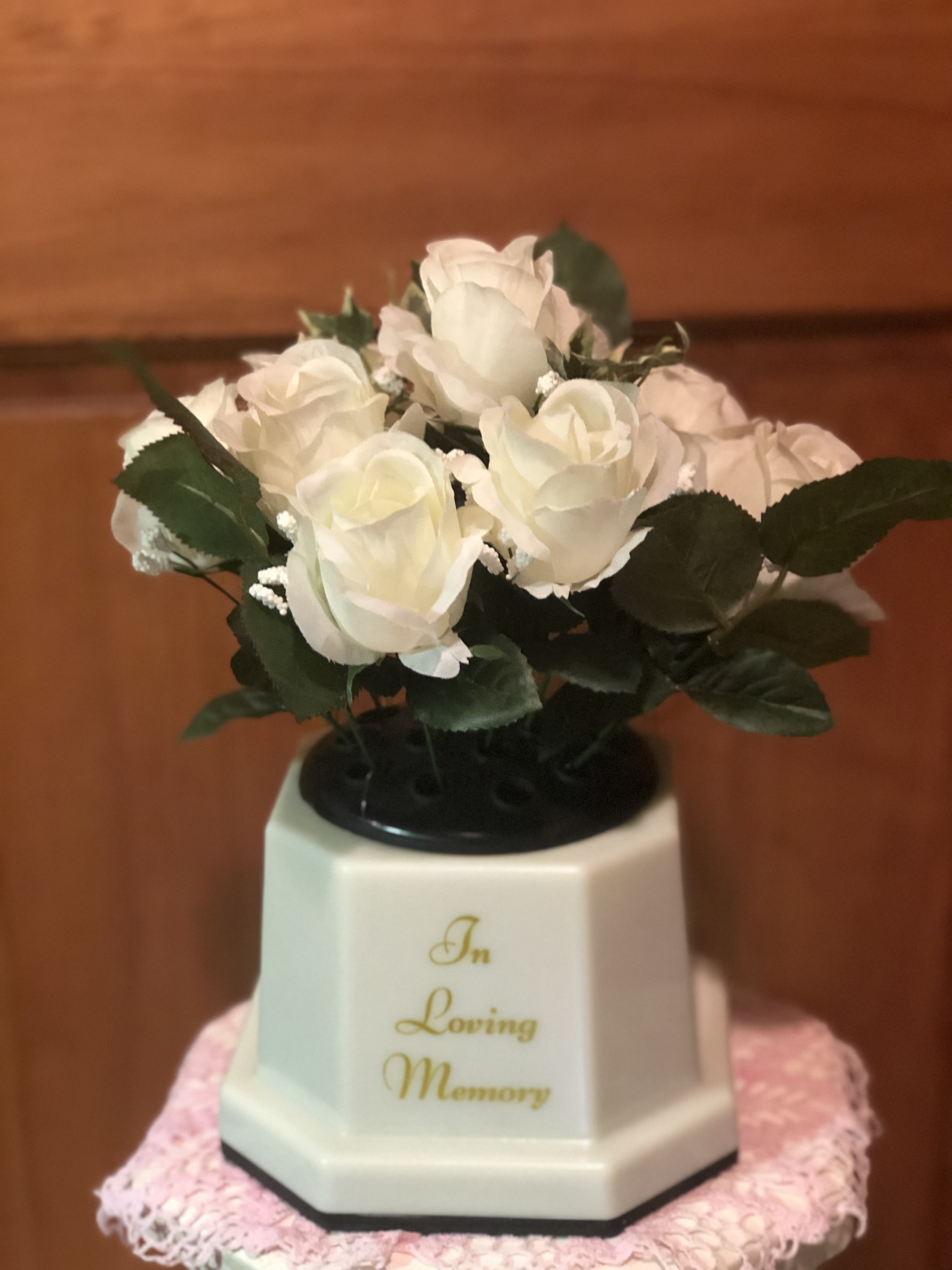 White roses in a memorial vase with "In Loving Memory" text