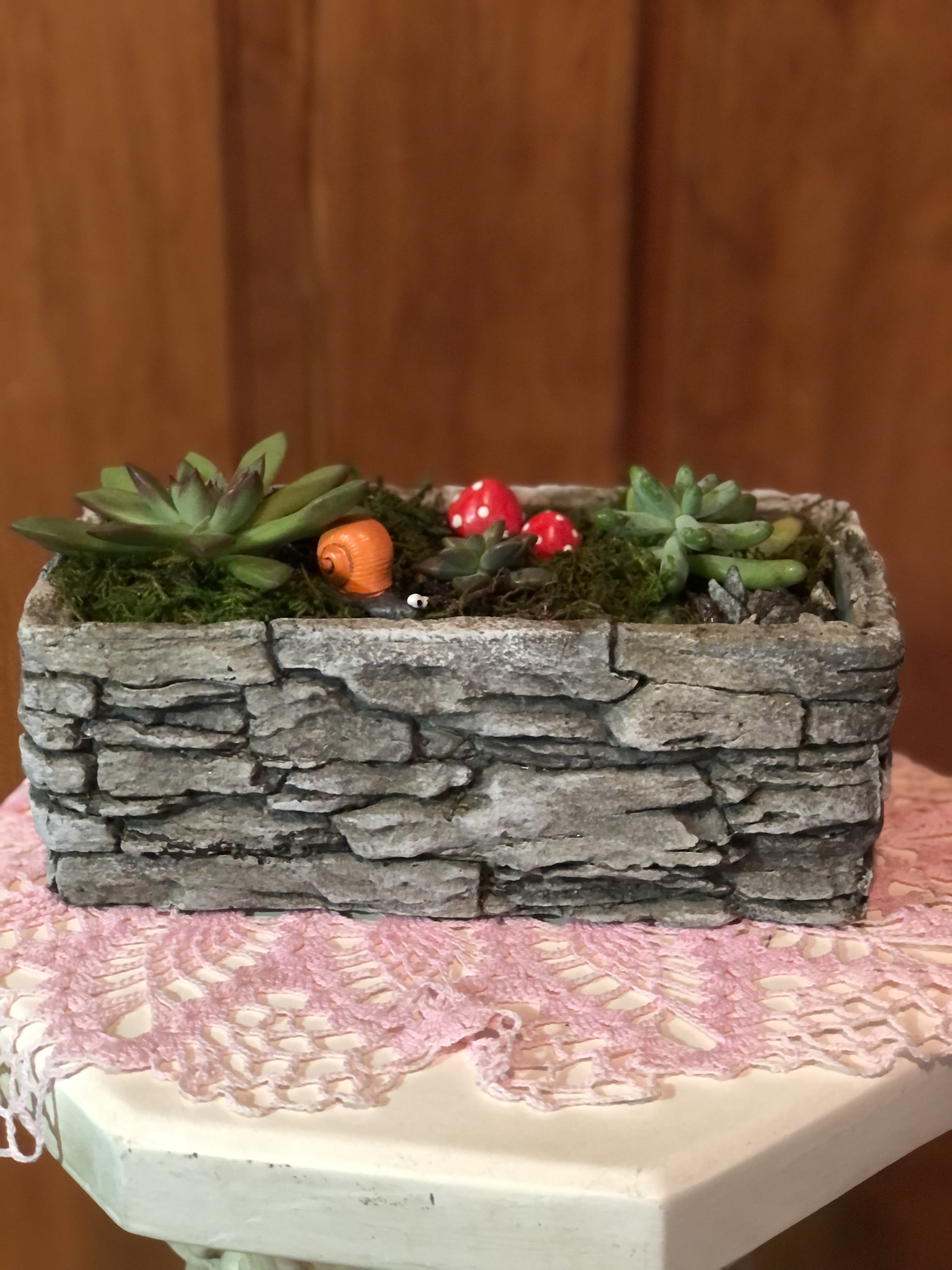 Succulent arrangement in a stone-look rectangular planter with small decorative mushrooms