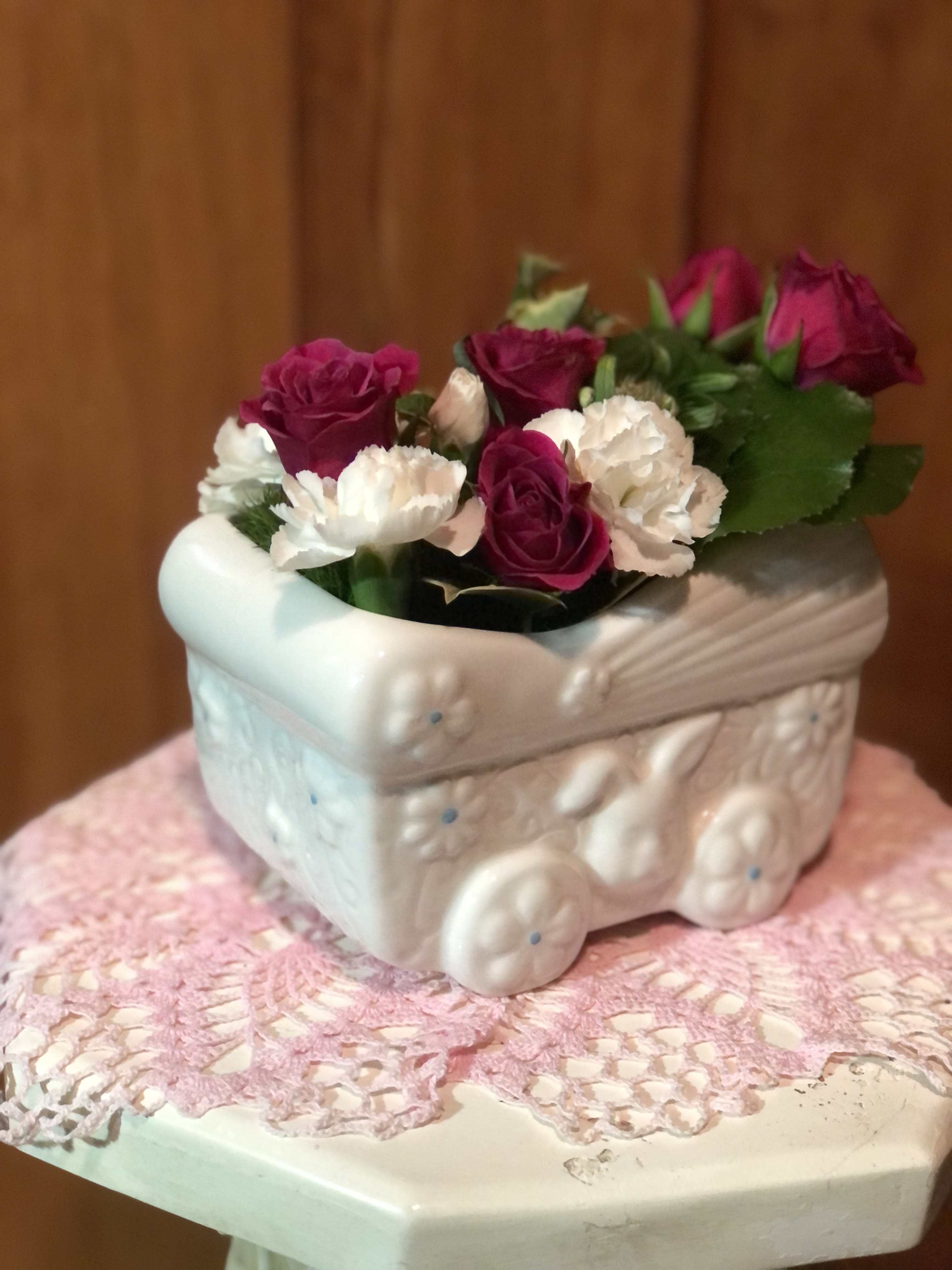Pink and white roses arranged in a white ceramic planter