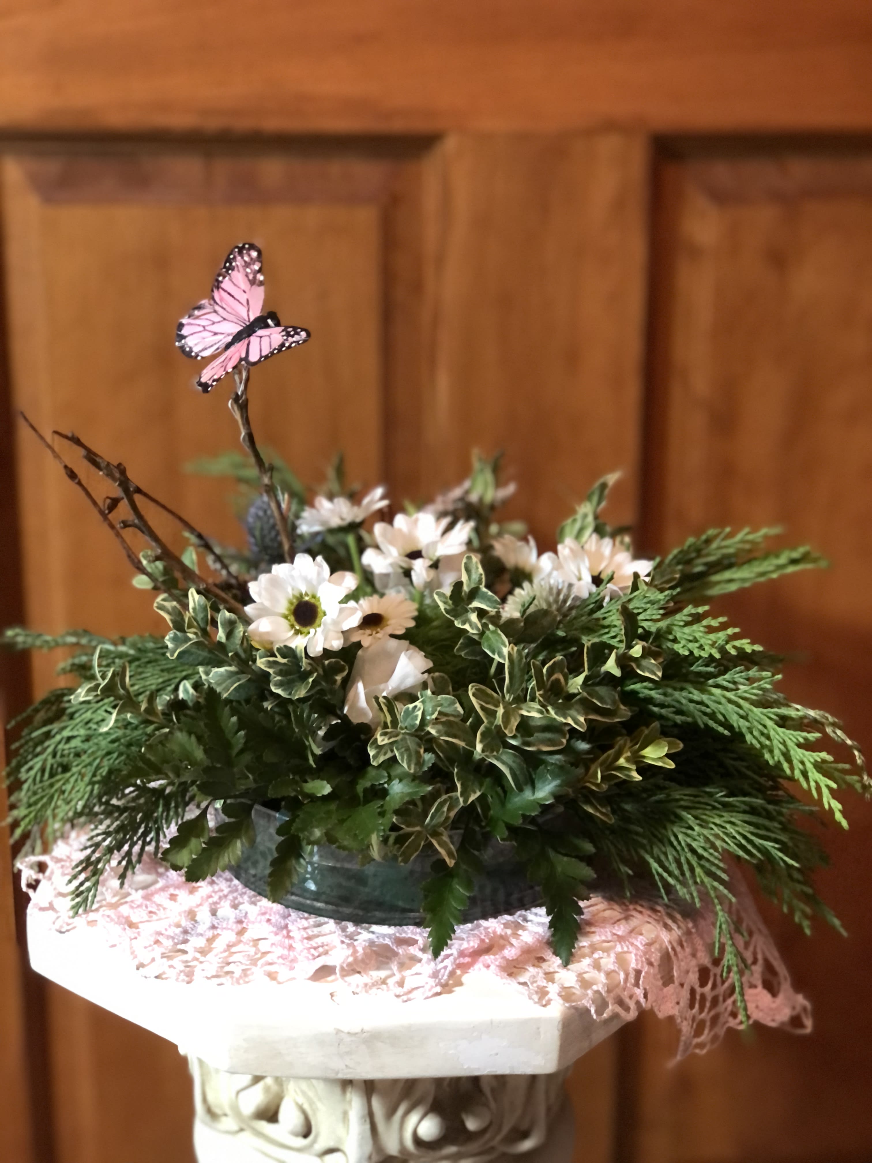 Low floral arrangement with white daisies and a pink butterfly pick