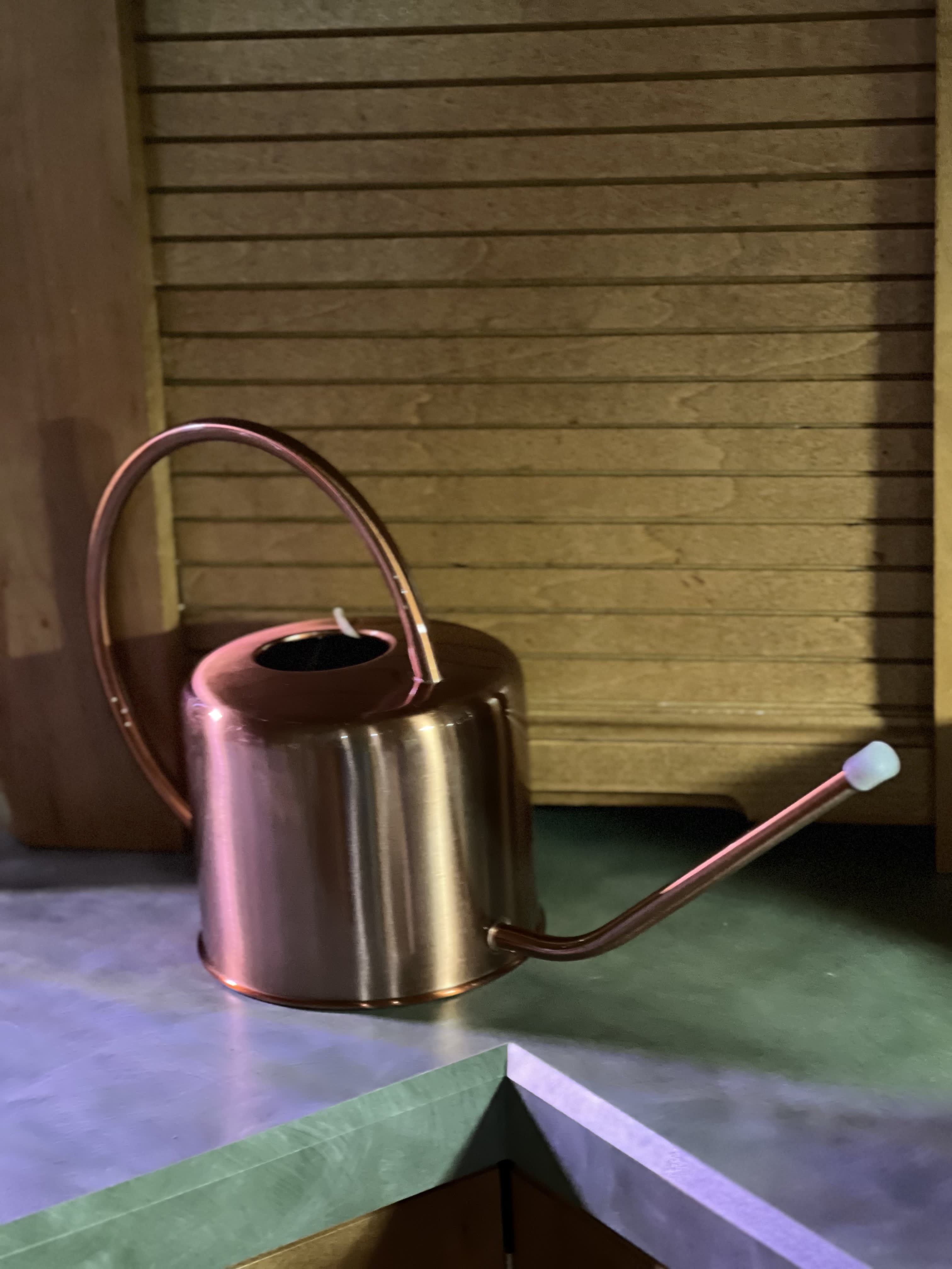 Copper watering can with a long spout on a countertop