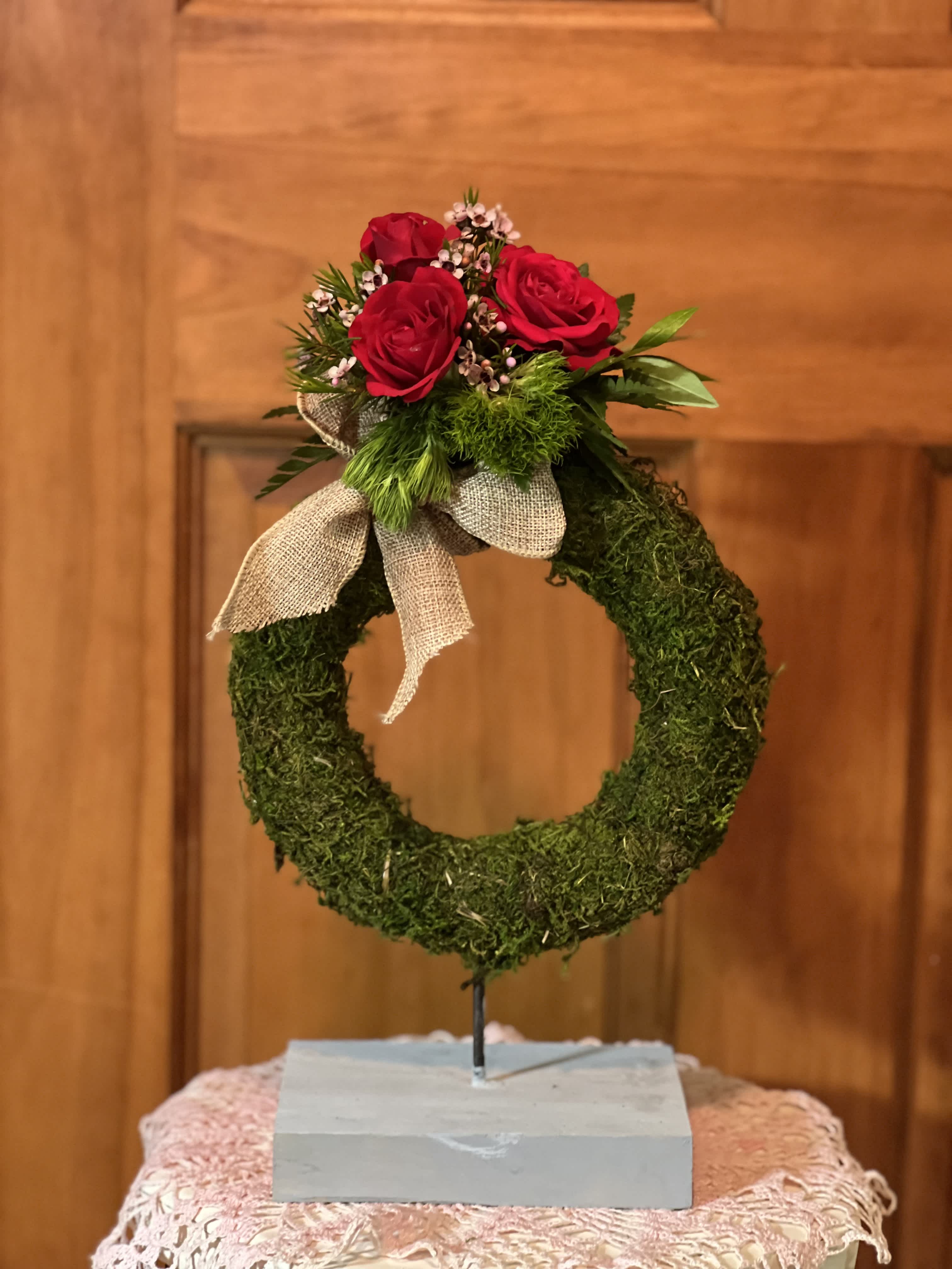 Red roses on a moss wreath with a burlap bow