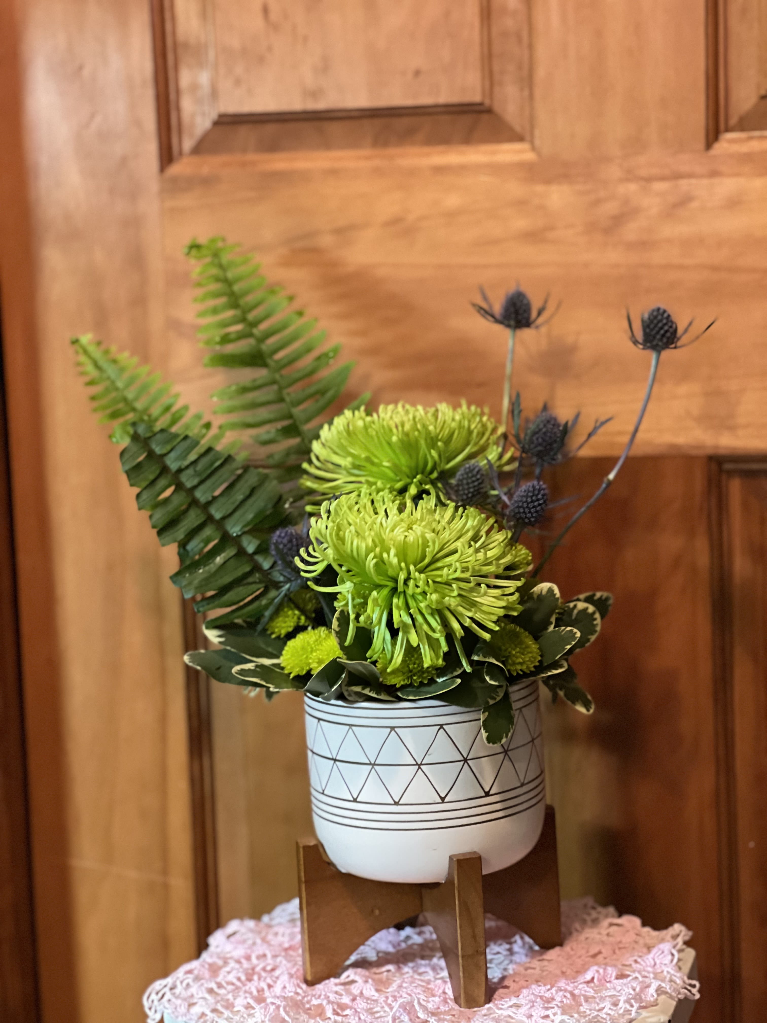 Green chrysanthemum arrangement in a patterned white pot