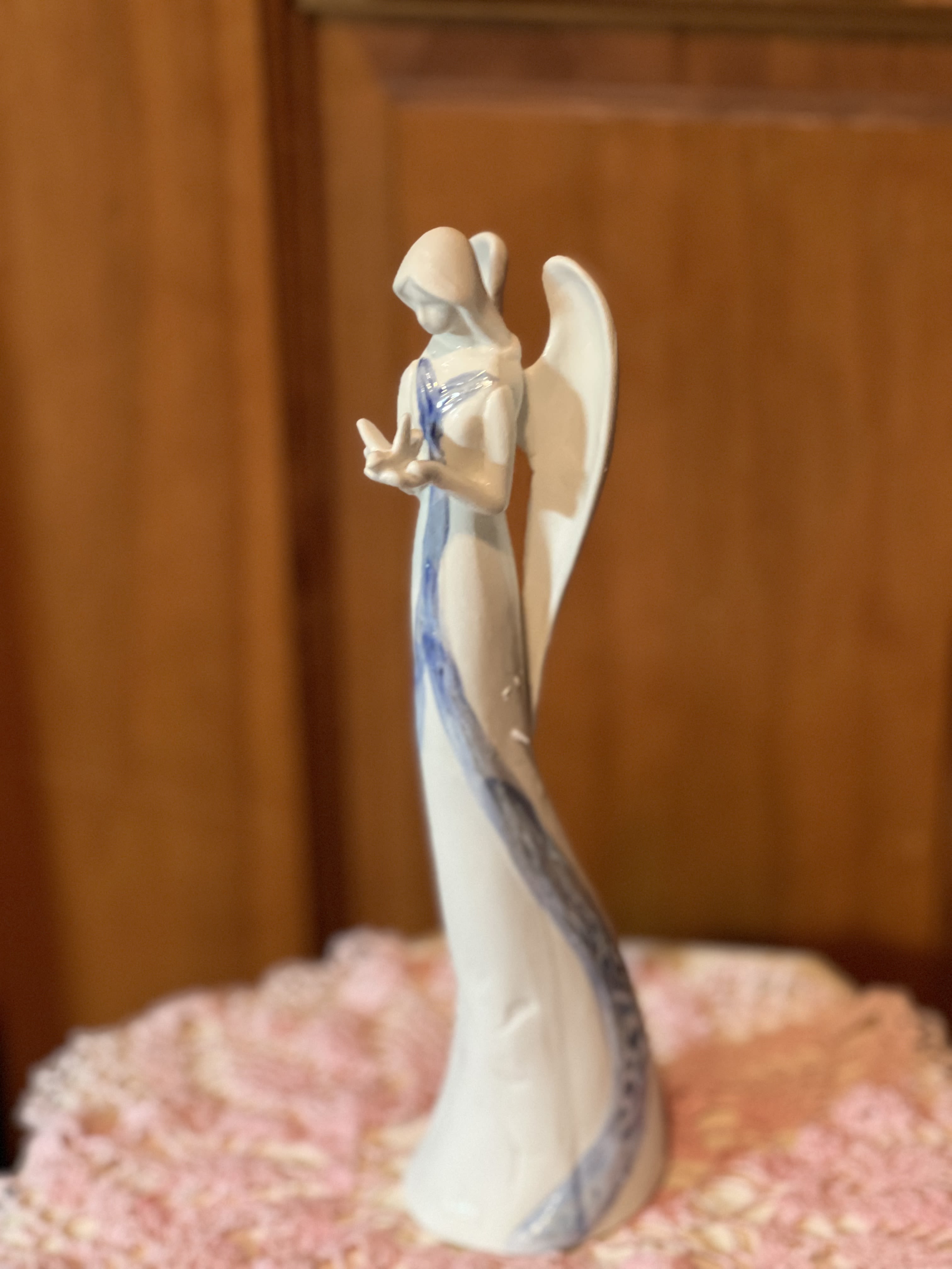 White angel figurine with blue accents on a pink floral base