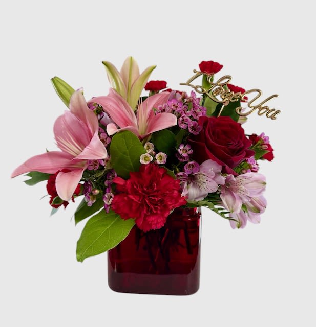 Bouquet of pink lilies, red roses, and carnations in a red vase