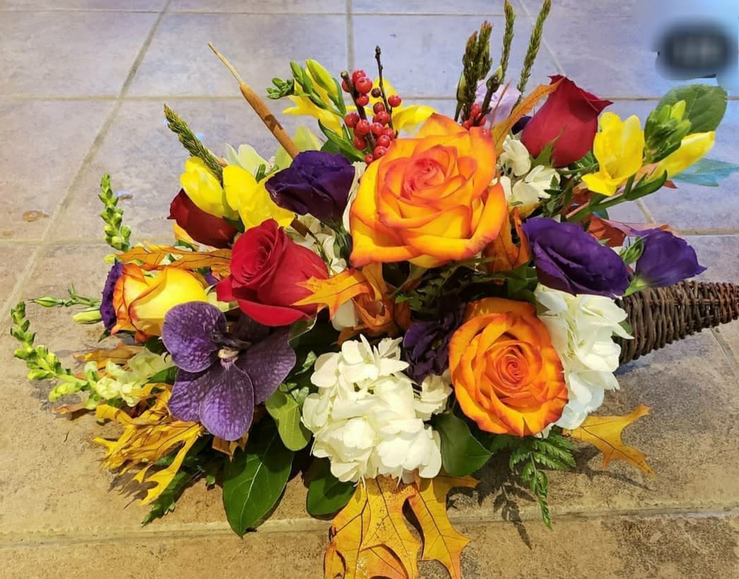 Bouquet of orange, red, purple, and white flowers with autumn leaves