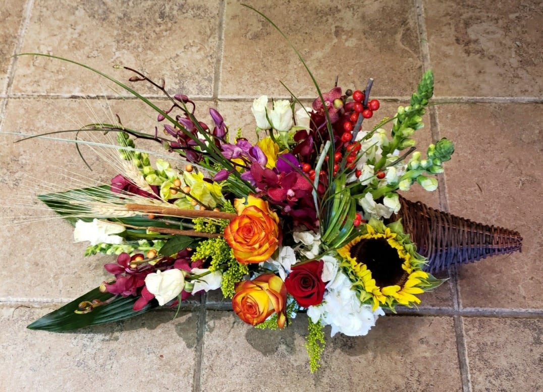 Colorful floral arrangement in a wicker cone basket with sunflowers and roses