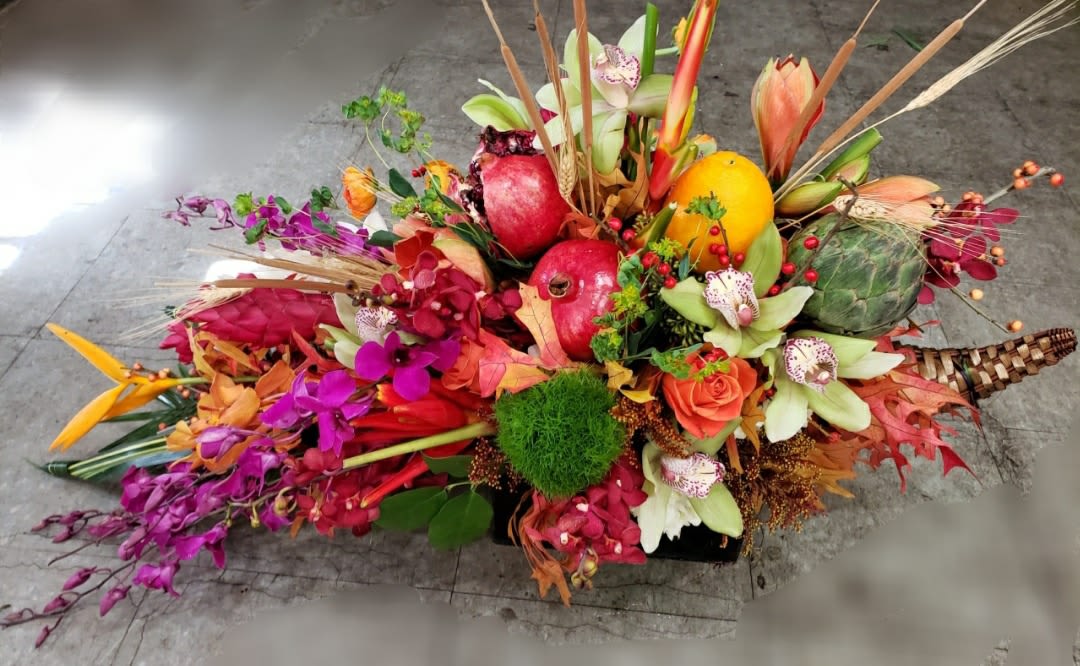 Colorful tropical floral arrangement with fruit in a low container