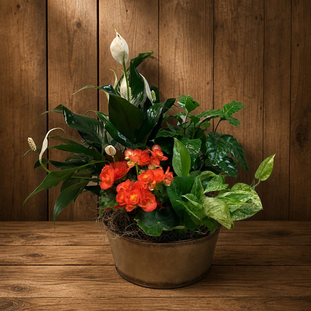 Mixed potted arrangement with white peace lilies and orange flowers in a bronze container