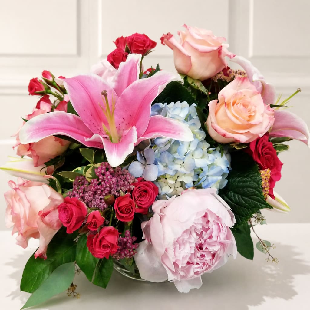 Mixed bouquet with pink lilies, roses, hydrangea, and peonies in a vase