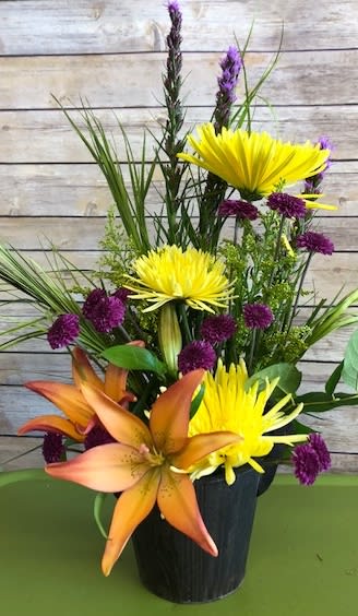 Orange lilies and yellow chrysanthemums in a black vase