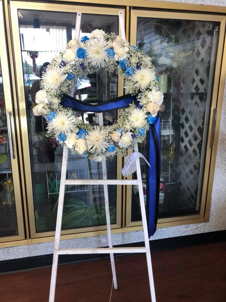 White and blue floral wreath on a standing easel with ribbon