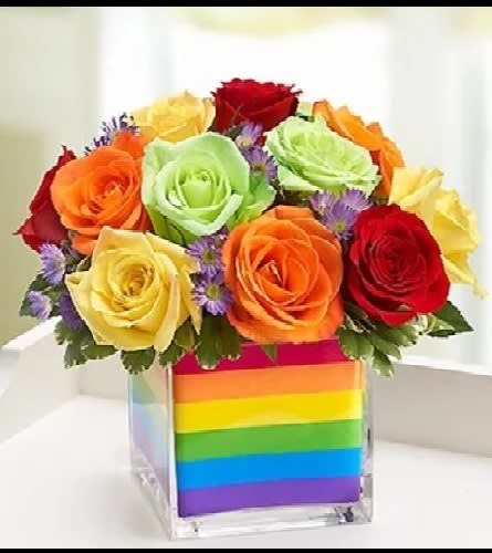 Rainbow rose bouquet in a clear cube vase with striped wrap