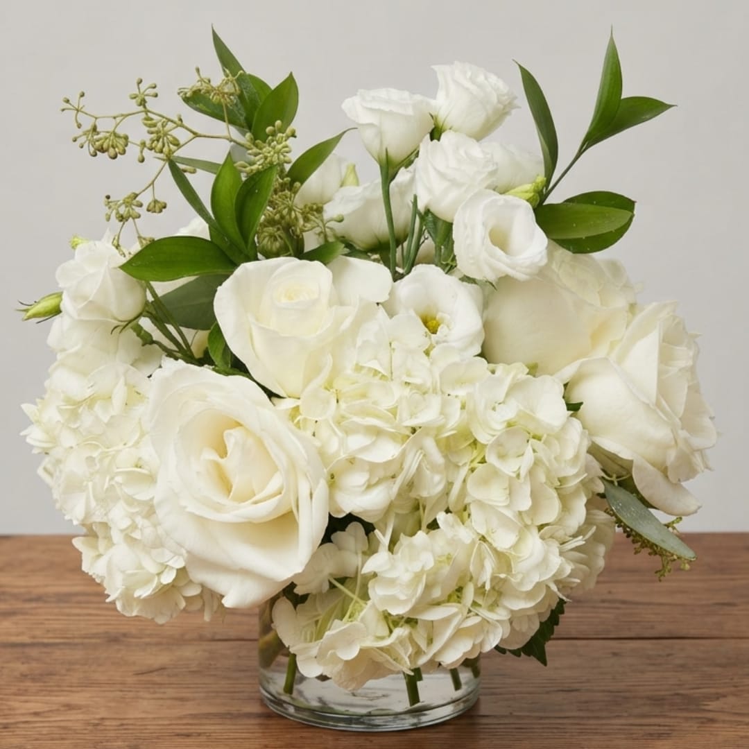 White roses and hydrangeas arranged in a clear glass vase