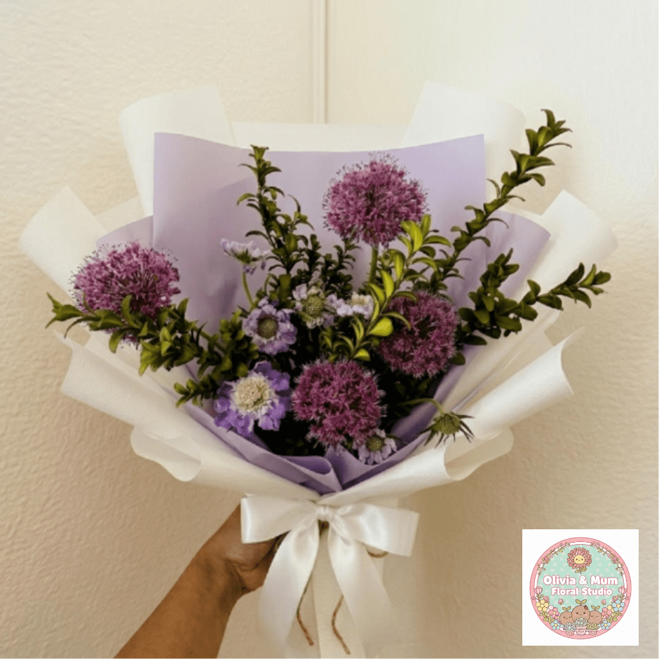 Royal Purple - Regal, striking, and bold—Royal Purple is designed for a love that stands out. Featuring the unique architectural beauty of purple allium and exotic scabiosa, this bouquet offers a one-of-a-kind silhouette for a one-of-a-kind partner.  This seasonal bouquet features:  Purple Allium  Lavender Scabiosa  Fresh Boxwood  Garden Greens  Presentation: Expertly wrapped in our signature textured paper and tied with satin ribbon. Prefer a vase? Add one to your cart to complete the look.  Personal Touch: We’ll include a custom card message with every order. You’ll be able to write your message at checkout.  Please Note: All flowers are subject to seasonal availability. If a specific bloom isn’t available, our designers will thoughtfully substitute with flowers in a similar shape, style, and color.  Standard size shown. Vase upgrade is optional.   Floral Care Guide  Your arrangement arrives in our signature "double wrap" and is nestled in a protective box. While the stems are secured with a wet wrap for transit they are ready for a full drink!   Unpack: Gently lift the bouquet from the box. Remove the plastic bag and wet towel from the stems. Trim &amp; Hydrate: Trim 1/2" off stems at an angle and place in a clean vase with cool water. Refreshed: Change water daily for a long-lasting bloom.