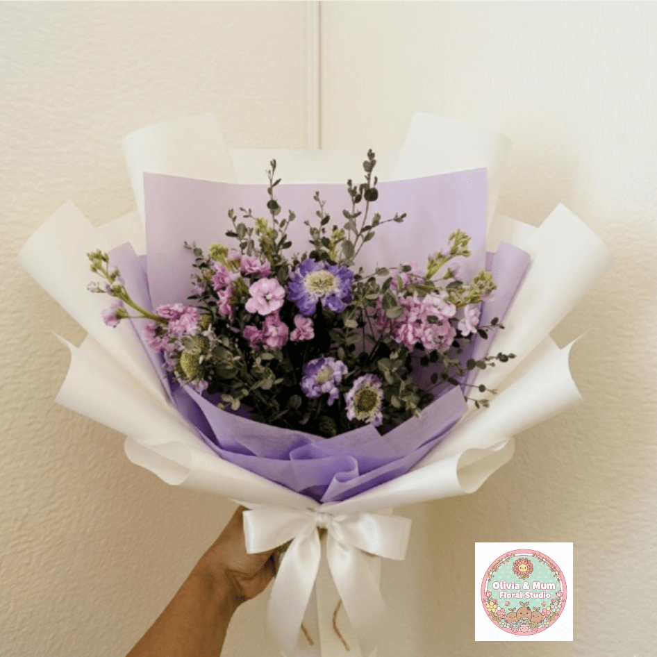 Twilight Mist - Moody, elegant, and mysterious—Twilight Mist captures the sophisticated beauty of the evening hour. Deep purples are softened by the silvery tones of eucalyptus, making this the perfect choice for an anniversary dinner under the stars.  This seasonal bouquet features:  Lavender Stock  Purple Scabiosa  Silvery Gunni Eucalyptus  Garden Greens  Presentation: Expertly wrapped in our signature textured paper and tied with satin ribbon. Prefer a vase? Add one to your cart to complete the look.  Personal Touch: We’ll include a custom card message with every order. You’ll be able to write your message at checkout.  Please Note: All flowers are subject to seasonal availability. If a specific bloom isn’t available, our designers will thoughtfully substitute with flowers in a similar shape, style, and color.  Standard size shown. Vase upgrade is optional.   Floral Care Guide  Your arrangement arrives in our signature "double wrap" and is nestled in a protective box. While the stems are secured with a wet wrap for transit they are ready for a full drink!   Unpack: Gently lift the bouquet from the box. Remove the plastic bag and wet towel from the stems. Trim &amp; Hydrate: Trim 1/2" off stems at an angle and place in a clean vase with cool water. Refreshed: Change water daily for a long-lasting bloom.  