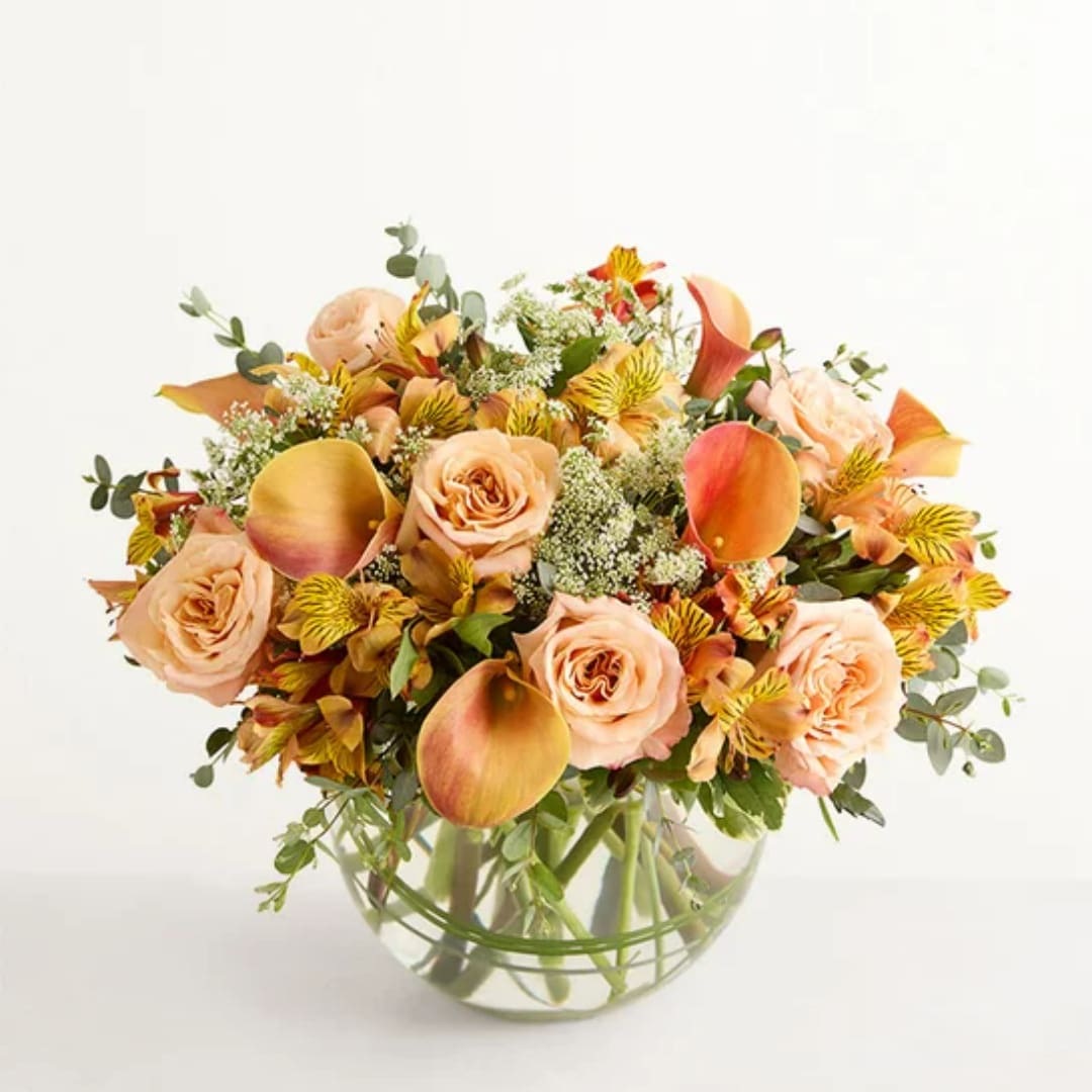 Peach roses and orange calla lilies in a clear glass vase