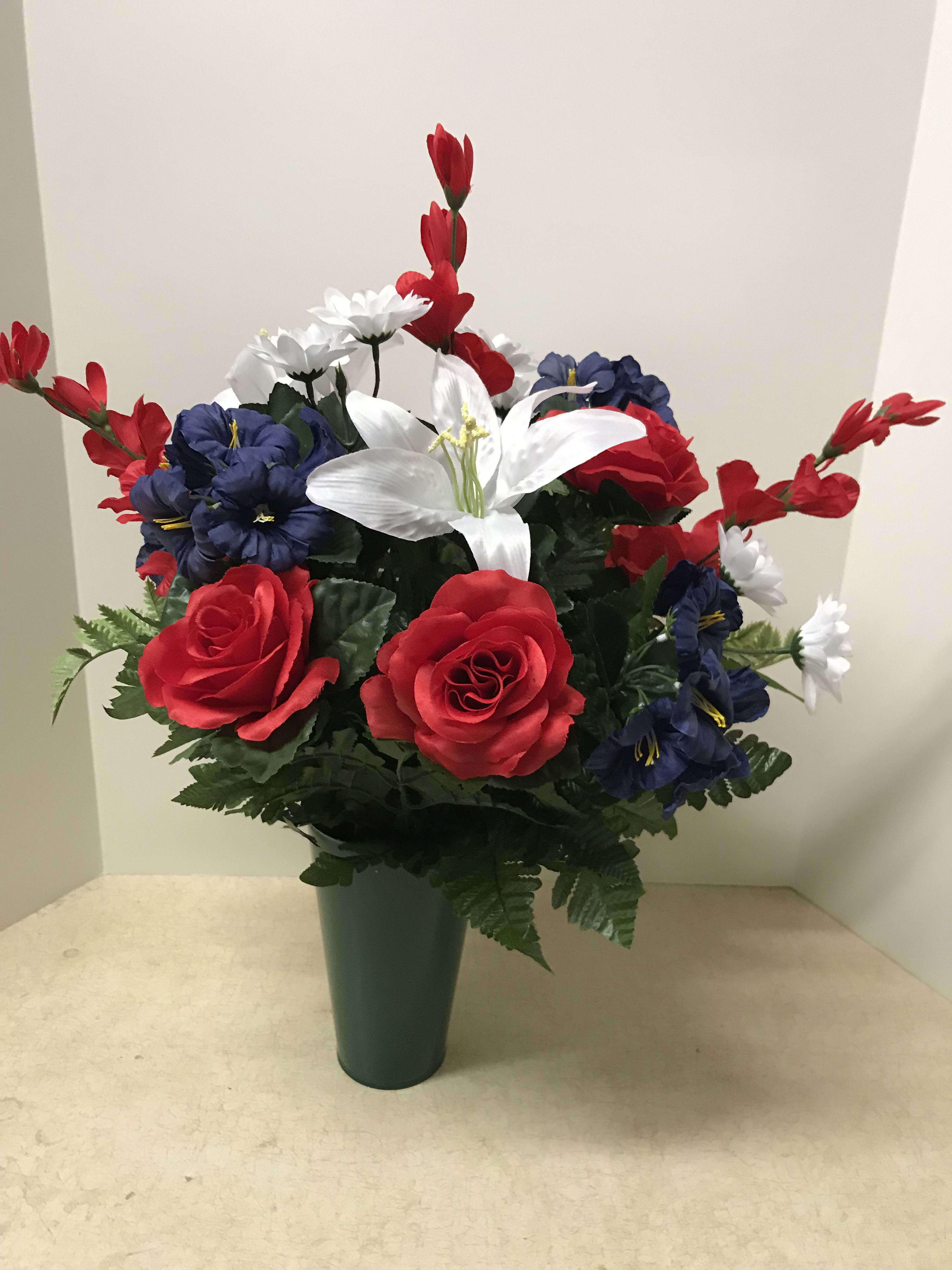 Artificial red, white, and blue flowers arranged in a green vase