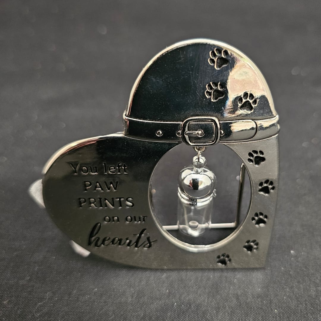 Heart-shaped memorial keepsake with paw prints and a small vial