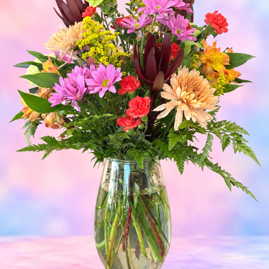 Mixed bouquet of colorful flowers in a clear glass vase