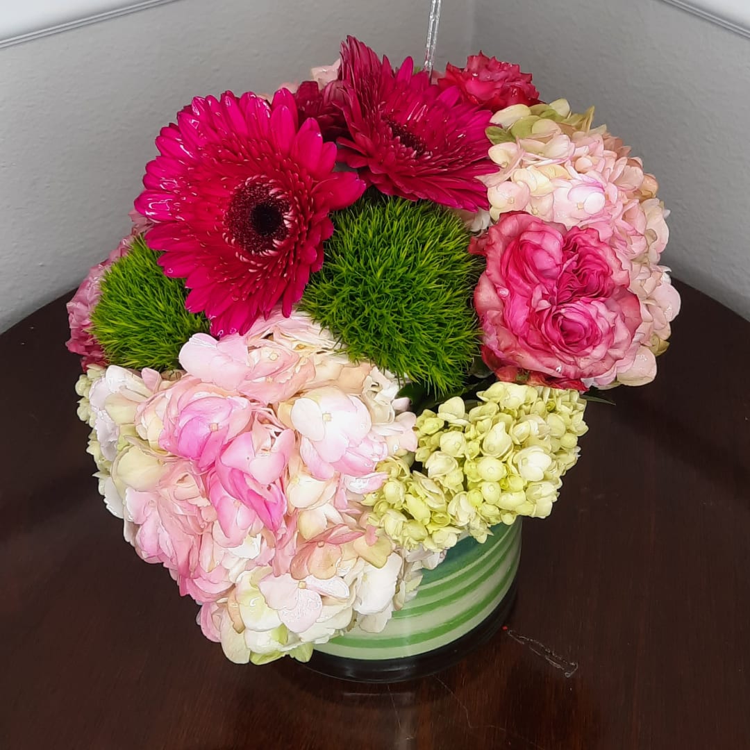 Pink and cream floral arrangement in a striped vase with bright green accents