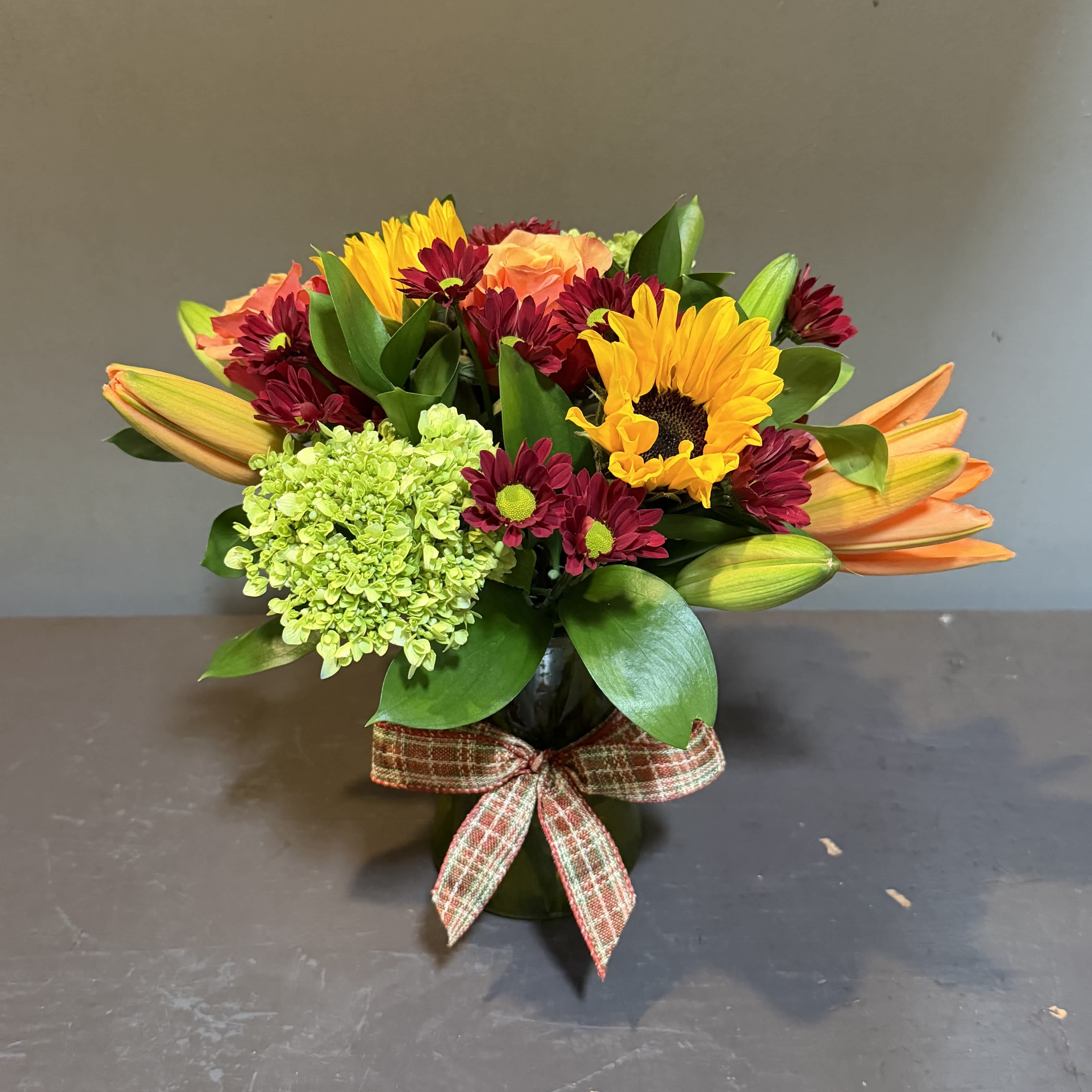 Mixed bouquet in a dark vase with a plaid ribbon