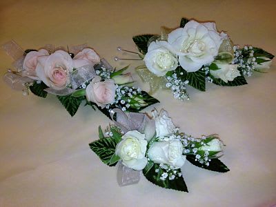 Three rose boutonnieres in pink and white with baby's breath