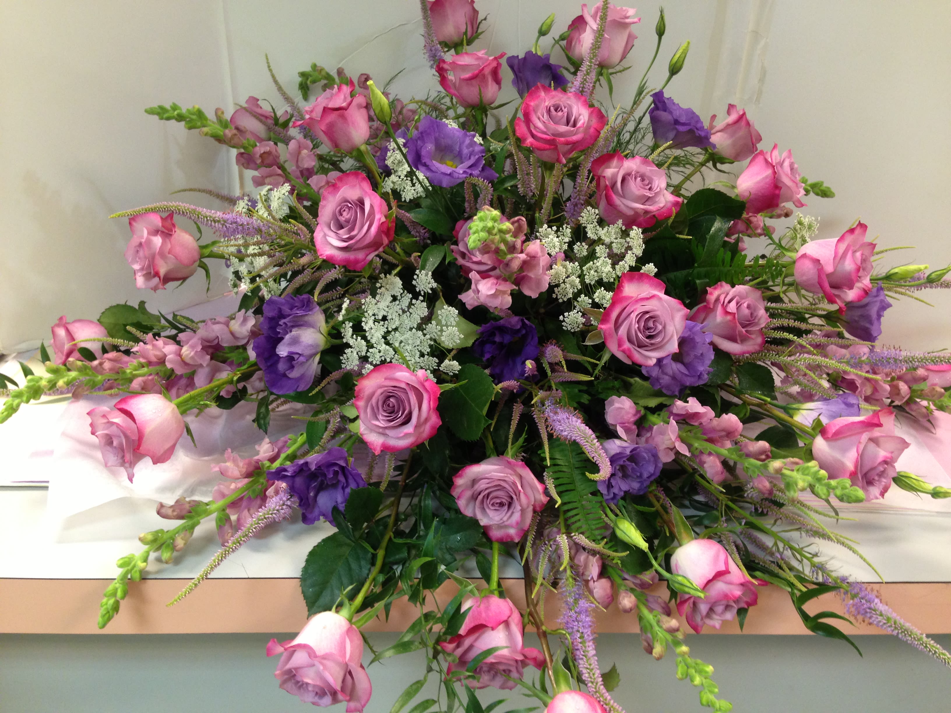 REST-IN-LAVENDER  CASKET COVER  -  Casket Spray is a wonderful way to commemorate a life abundant in beauty and love.  LAVENDER ROSES , PURPLE  LISIANTHUS ,  VERONICA , LAVENDER , SNAPDRAGONS, ASSORTED GREENS. Designed &amp; Photographed in our Store. Not a  Library Picture.