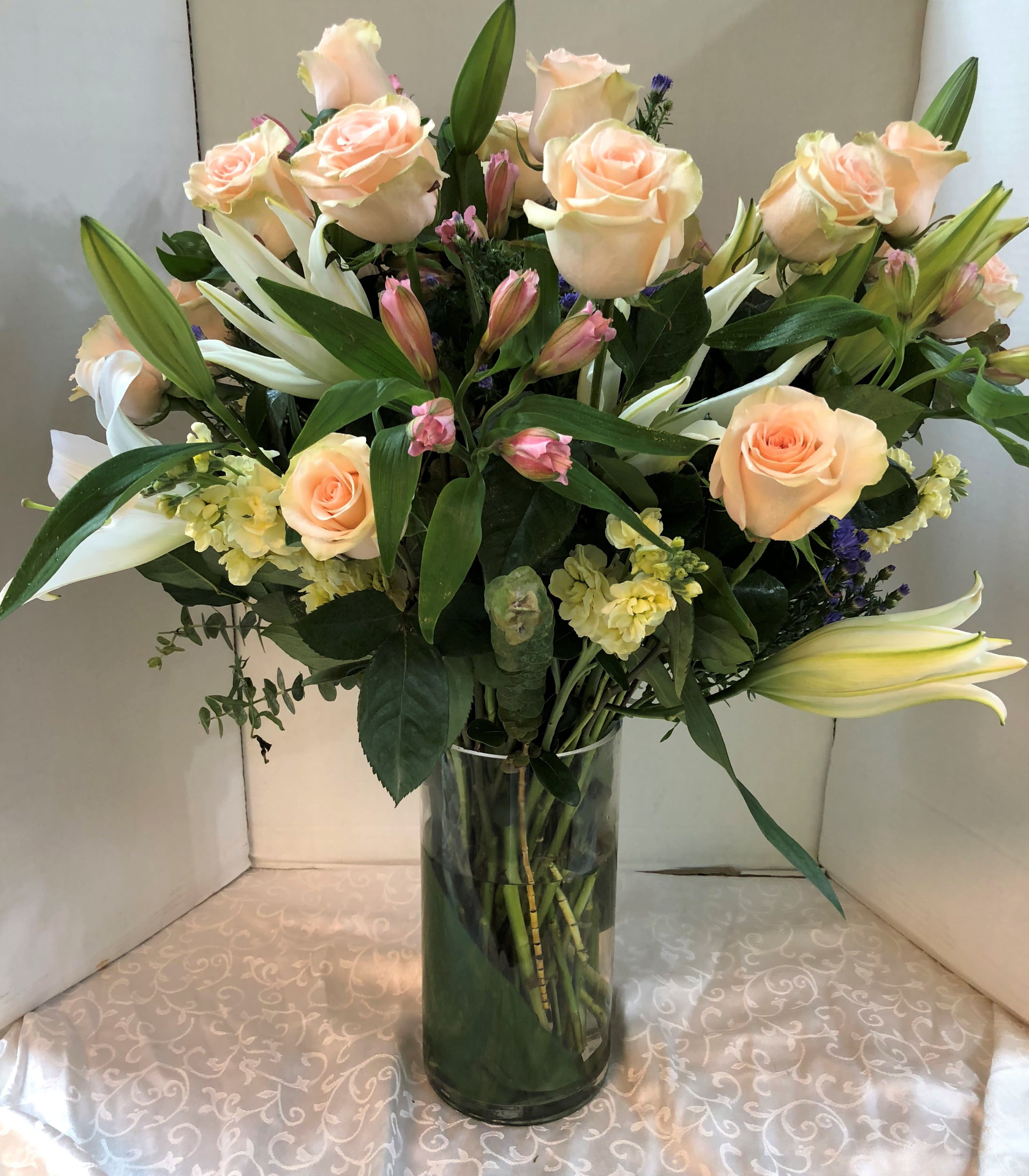 Bouquet of peach roses and white lilies in a glass vase