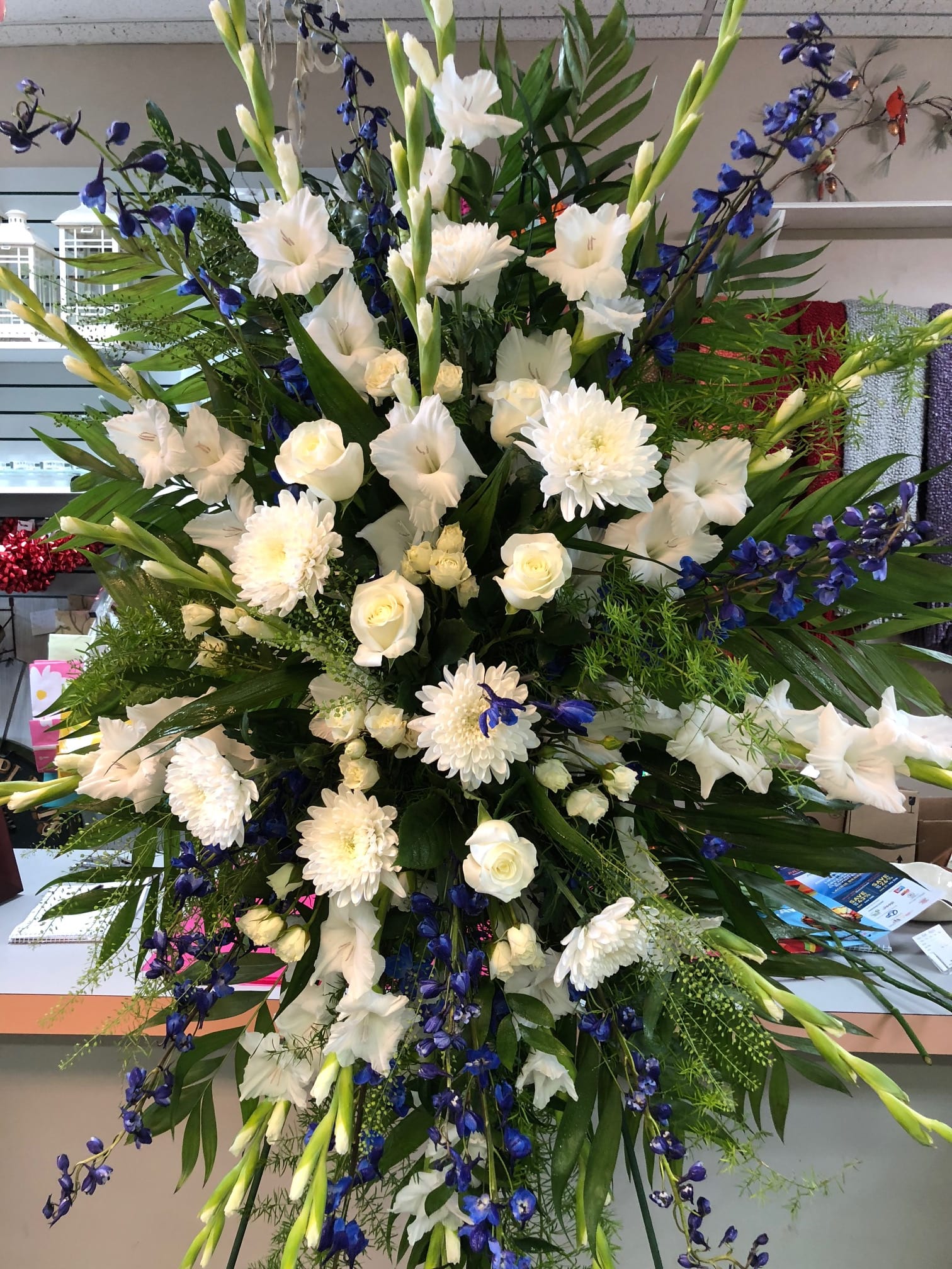 Large standing floral spray with white flowers and blue accents