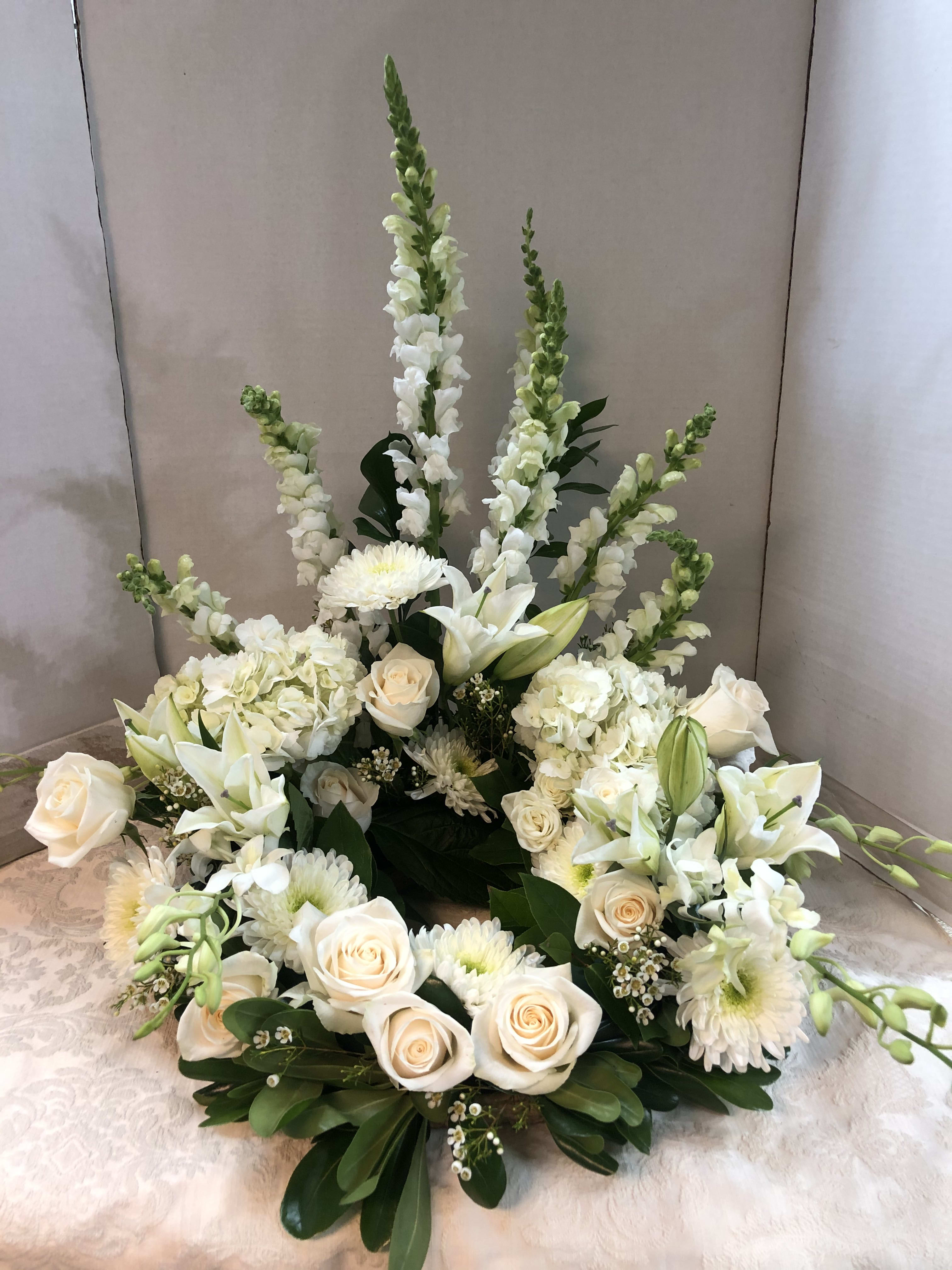 White floral arrangement with roses, lilies, and tall snapdragons