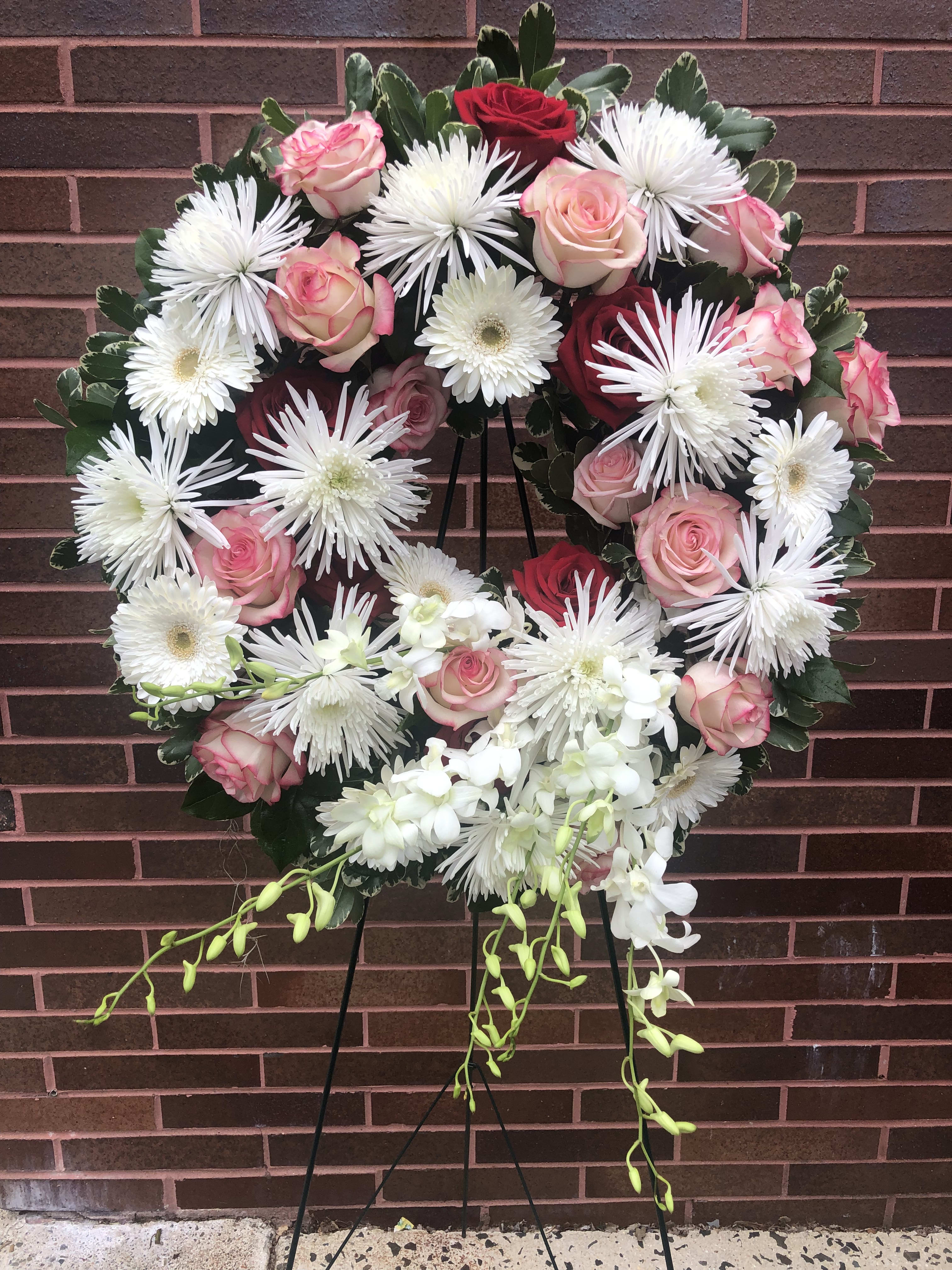 Heart-shaped floral wreath with pink and red roses and white daisies