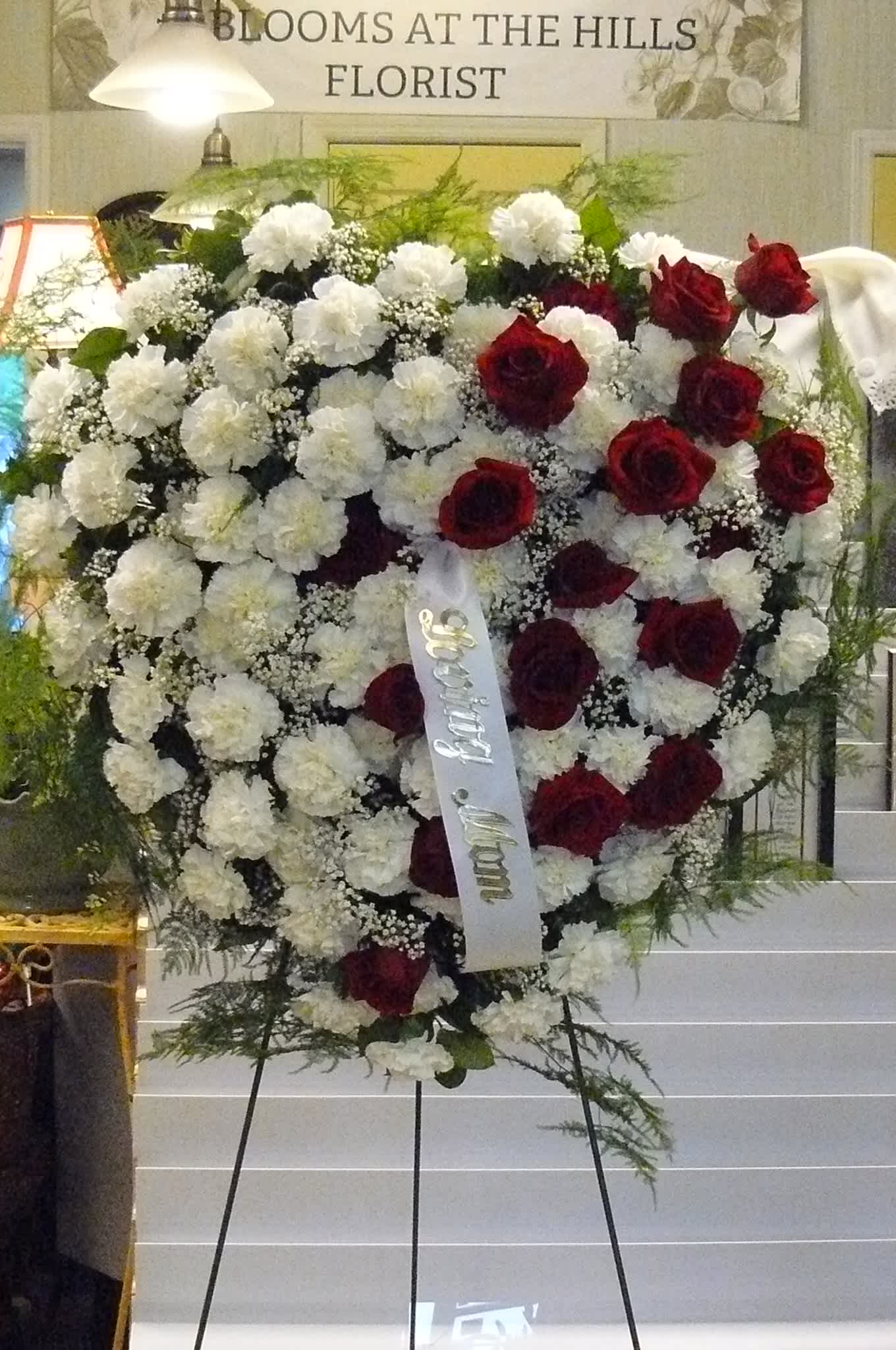 Heart-shaped standing spray of red roses and white carnations on an easel