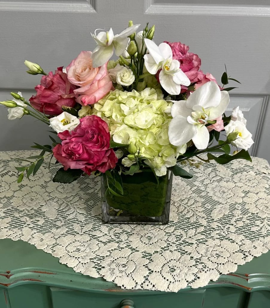 Pink and white floral arrangement in a square glass vase