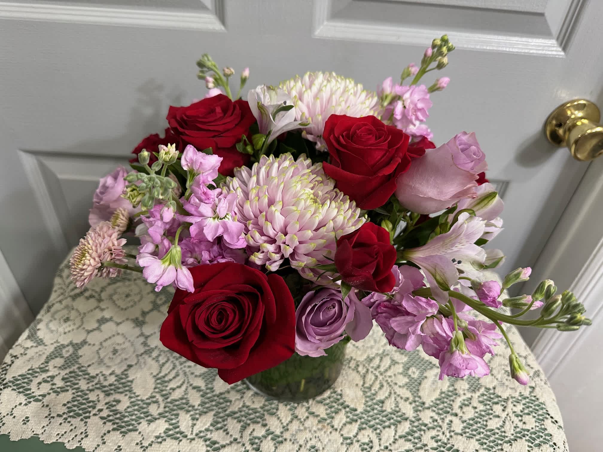 Bouquet of red and lavender roses with pink and white blooms in a glass vase