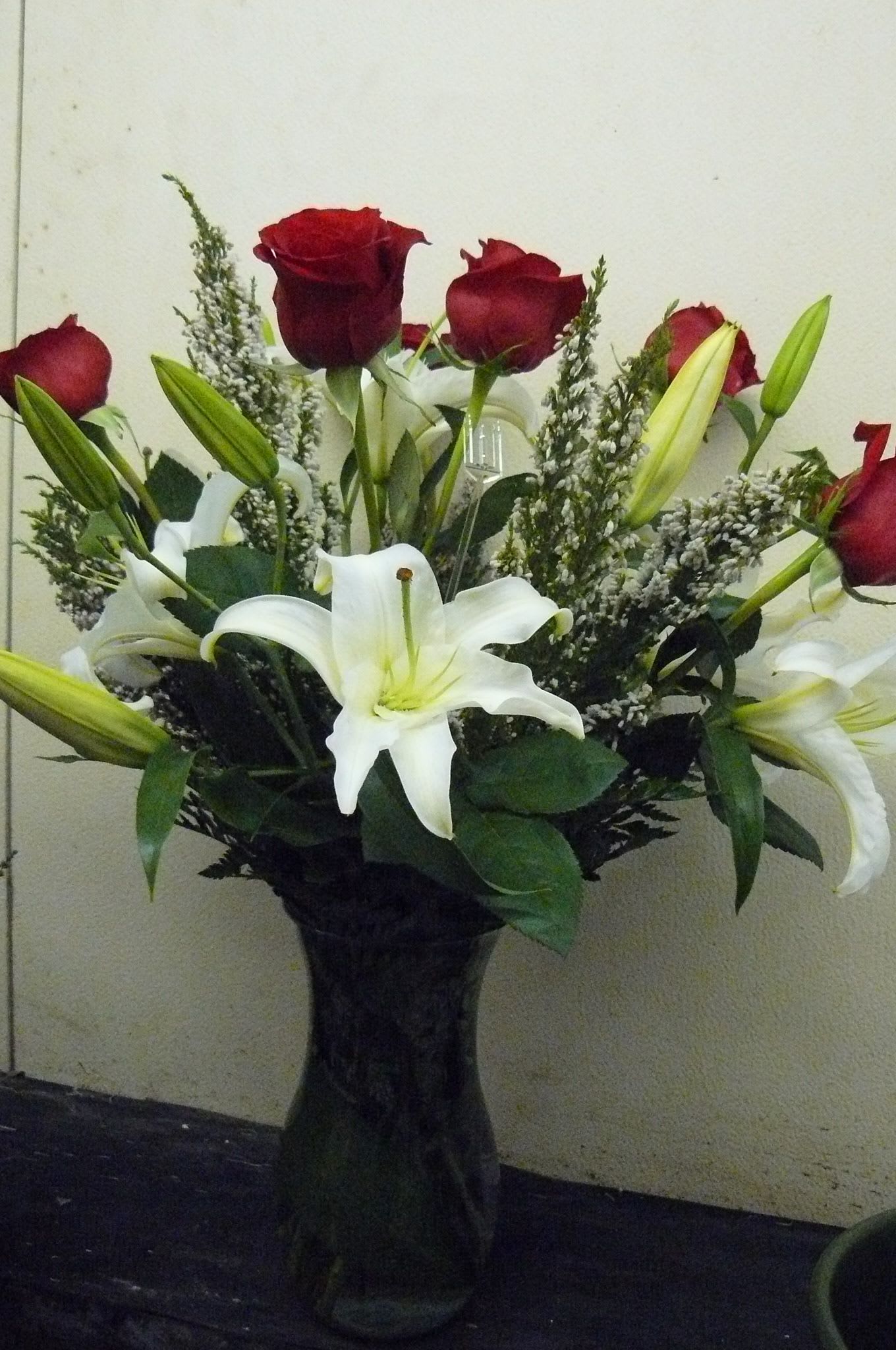 Bouquet of red roses and white lilies in a dark vase