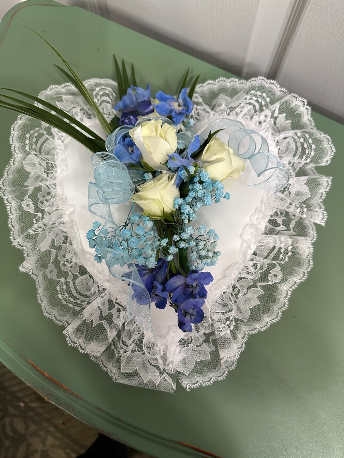 Heart-shaped bouquet of white roses and blue flowers with lace trim